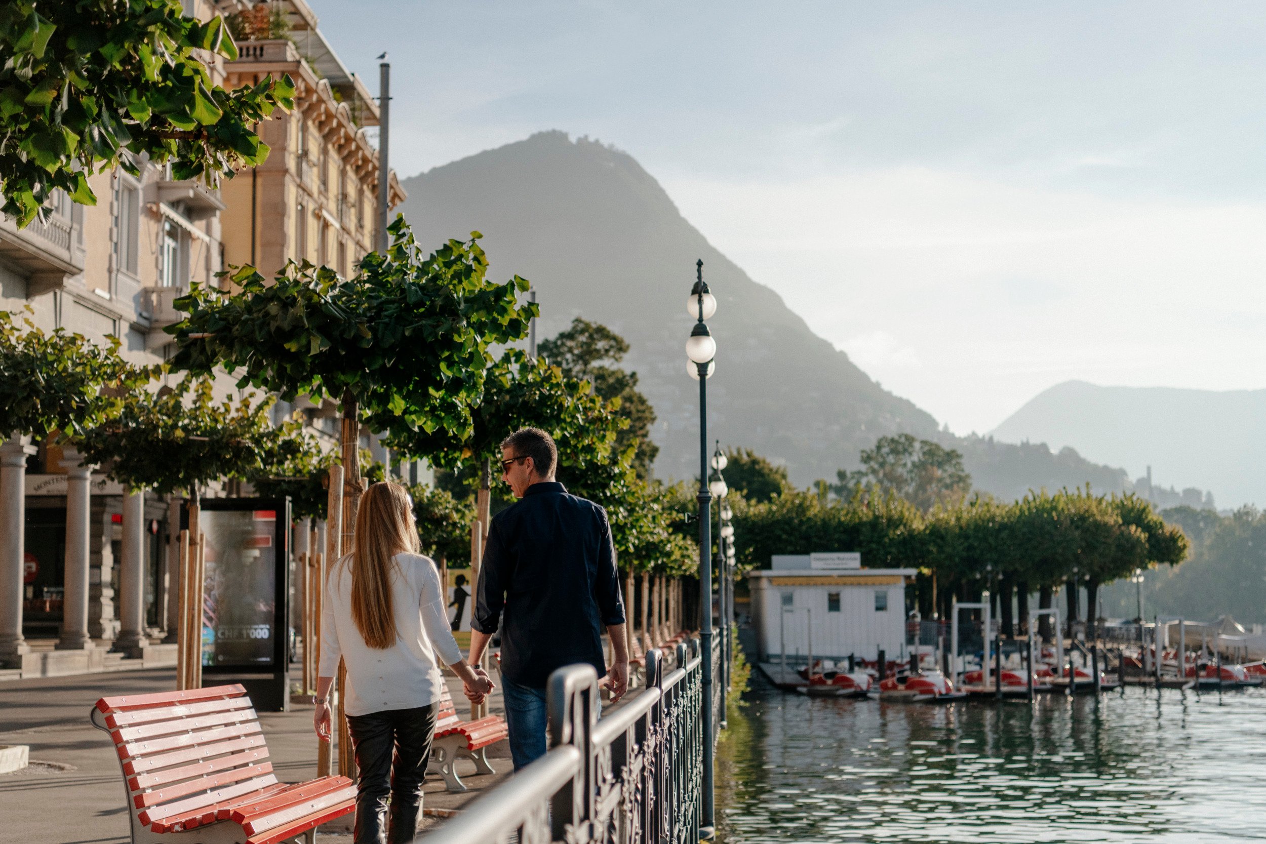 Couple marchant sur une promenade au bord d'un lac avec une montagne en arrière-plan