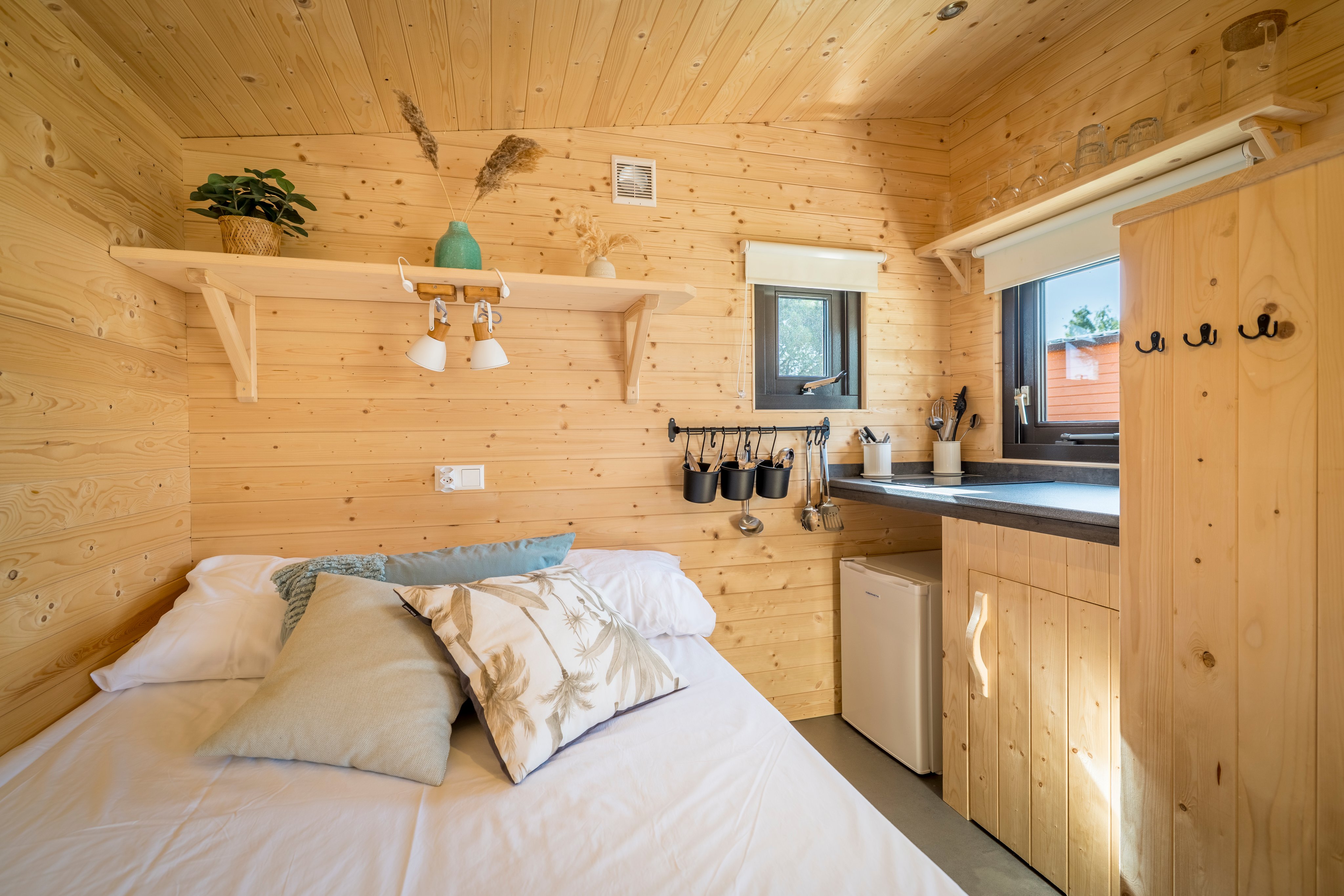 Un lit se trouve dans un logement locatif en bois, à côté d'une kitchenette.