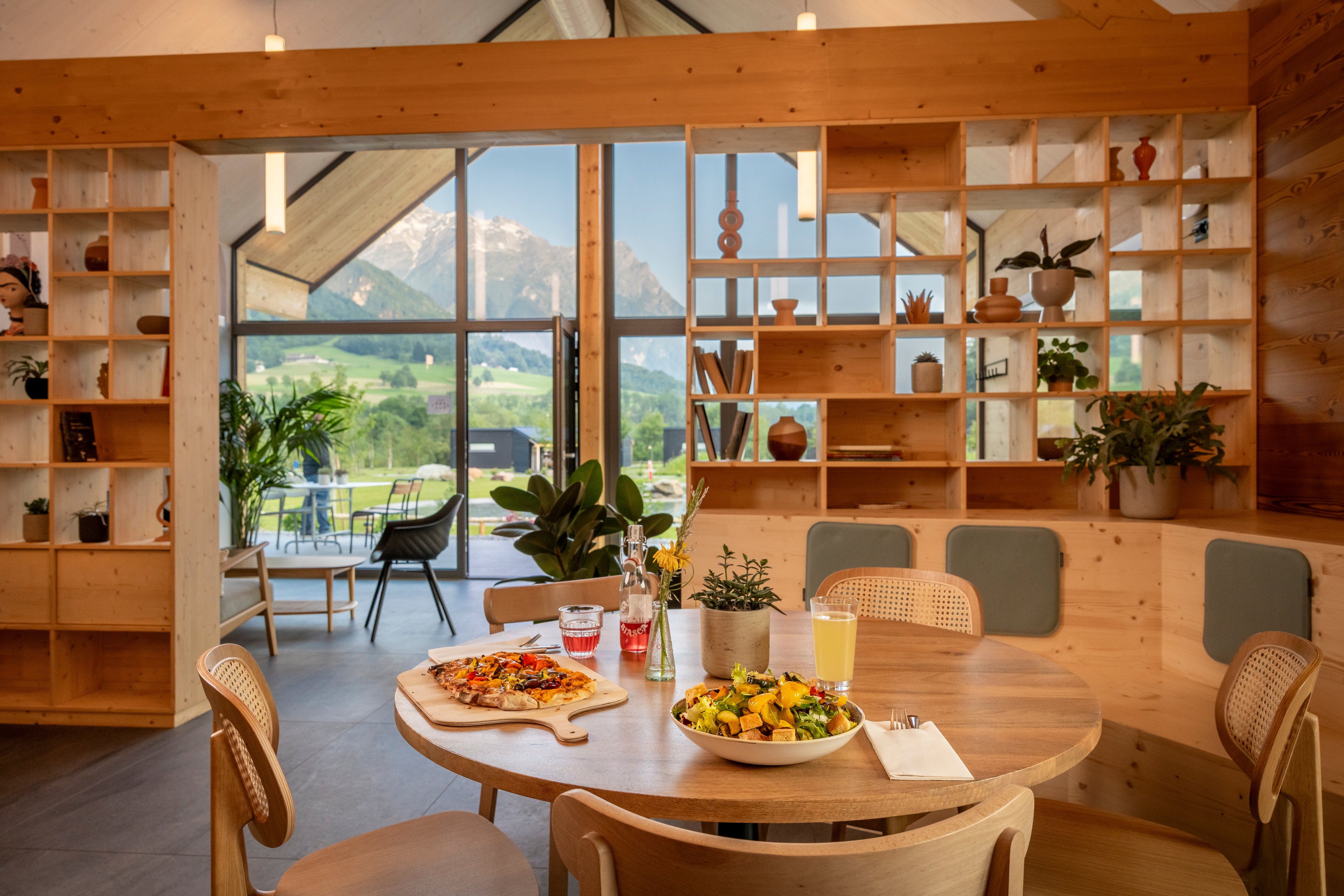 Une table avec de la nourriture, à l'arrière-plan une belle vue sur les montagnes à travers une vitre.