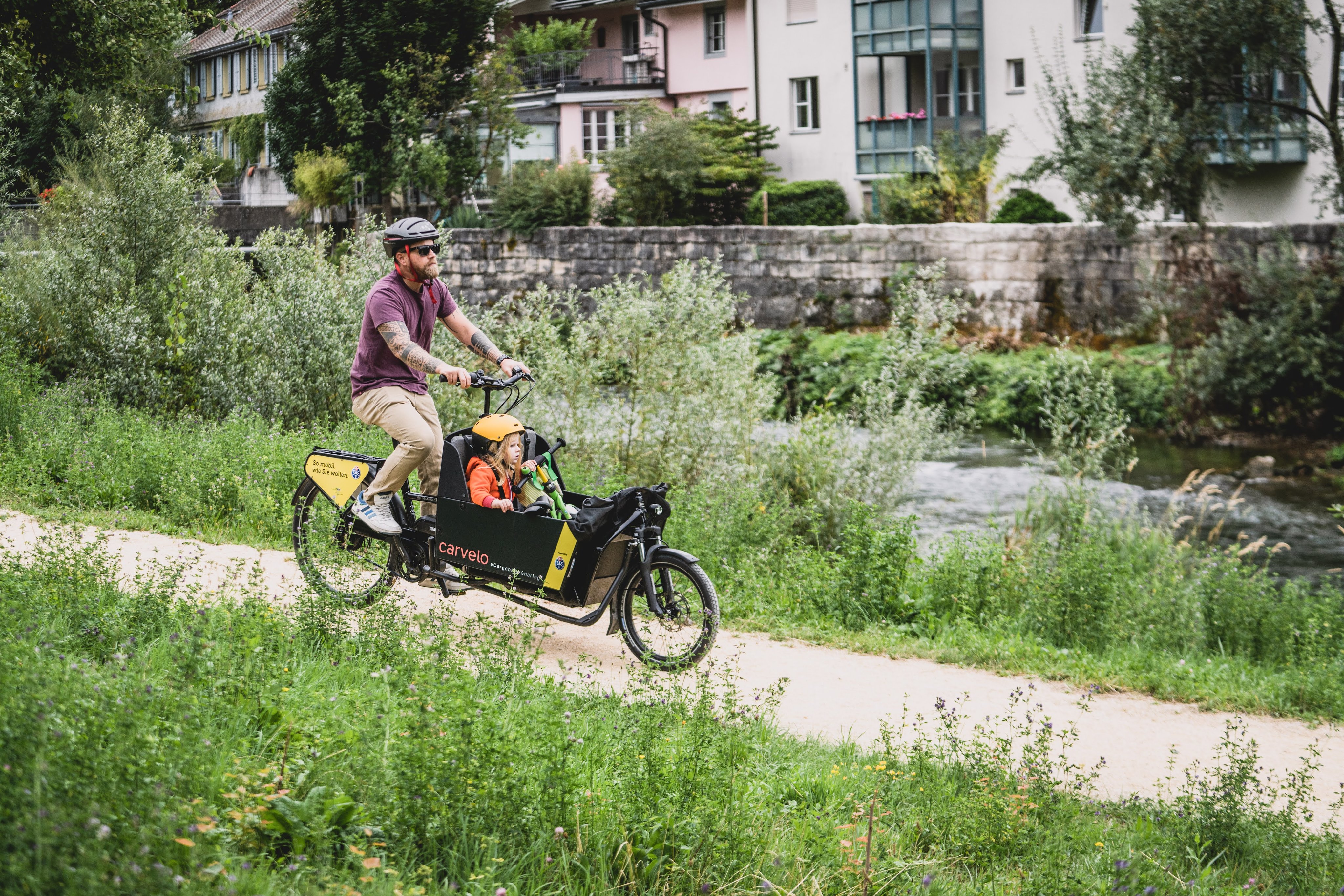 Un homme en balade avec sa fille et le vélo cargo électrique TCS.