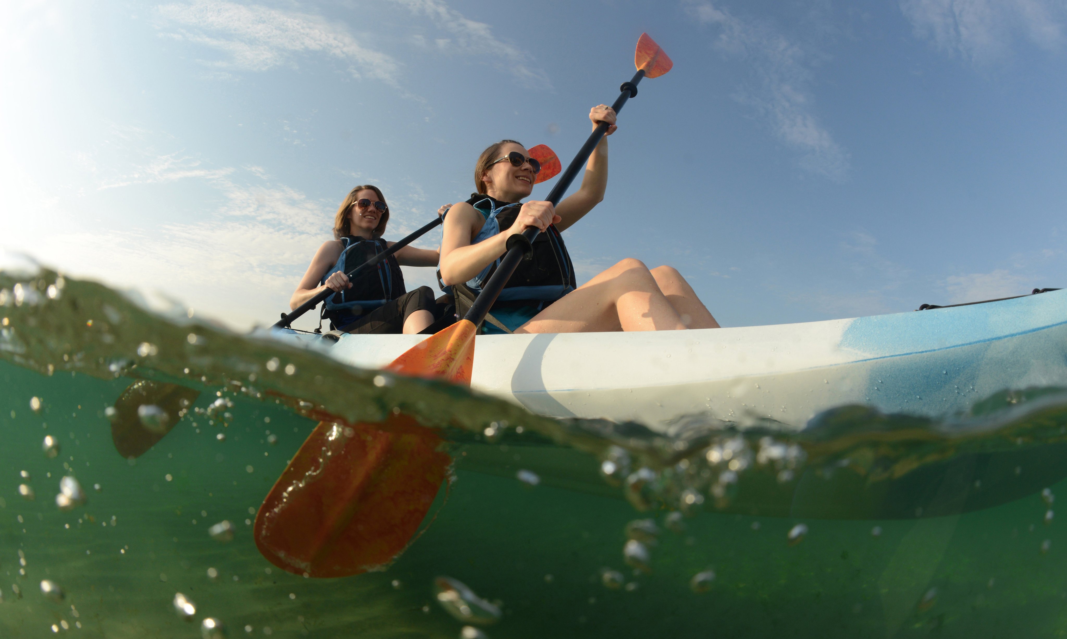 Two young women paddling in a blue kayak