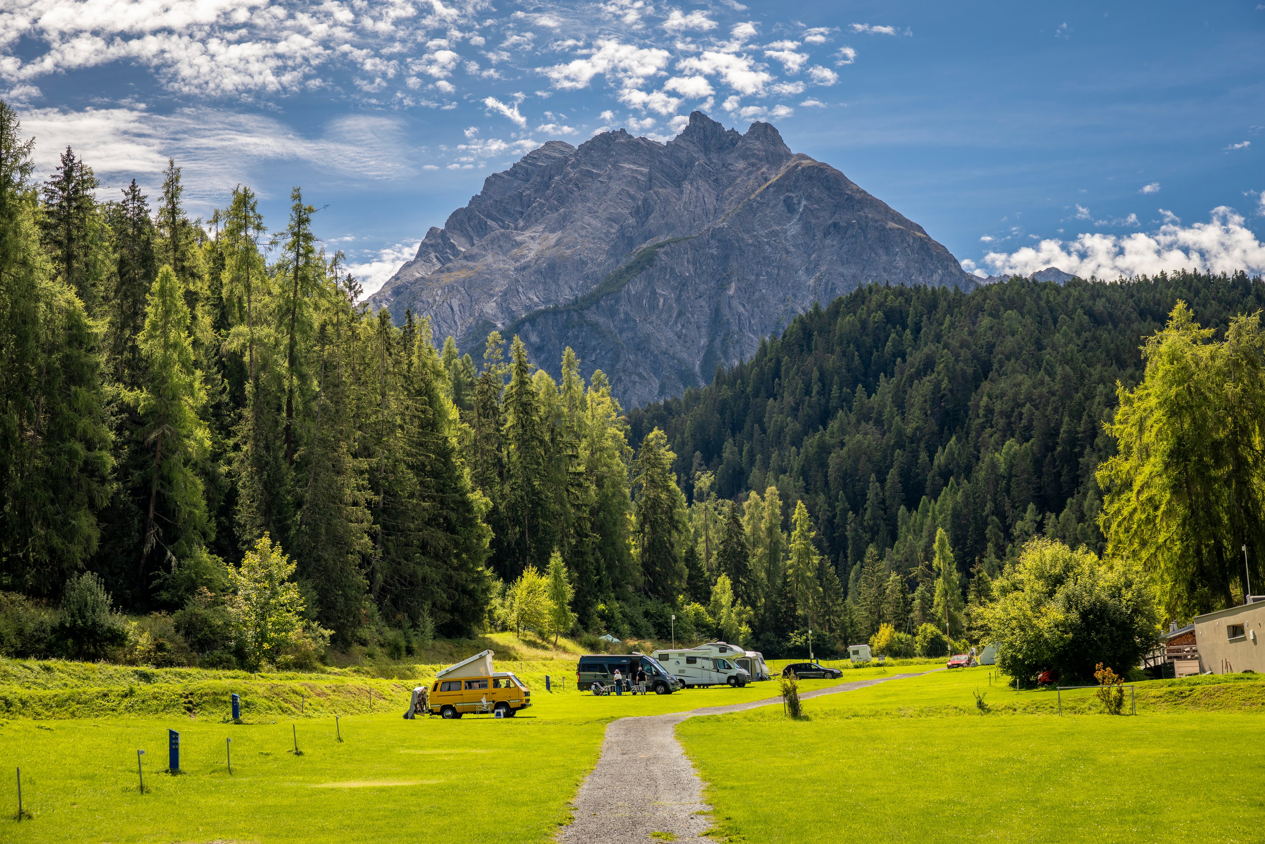 Auf einem Campingplatz vor einem markanten Berg stehen mehrere Camper.