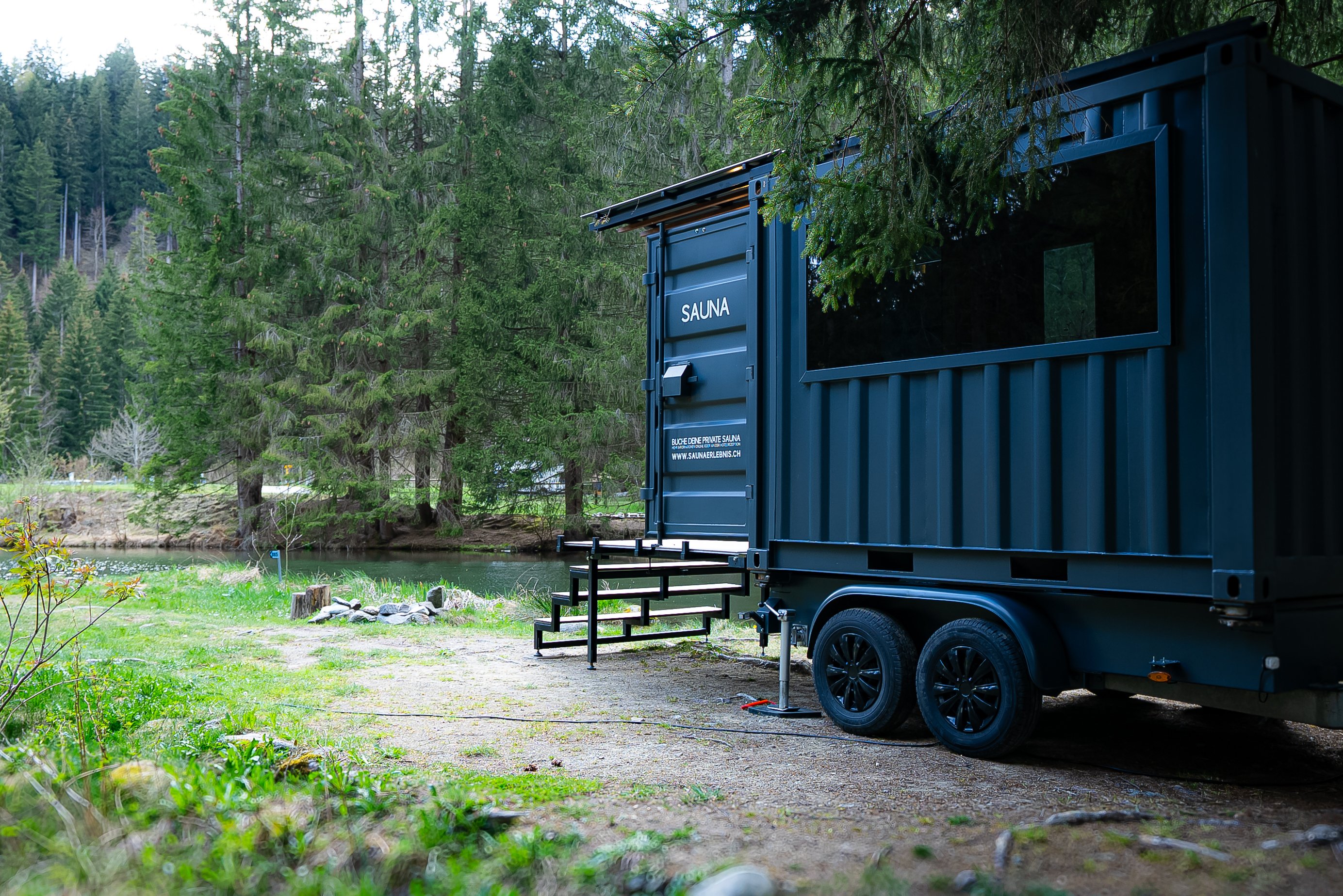 Exterior view of a sauna next to a small lake in the forest.