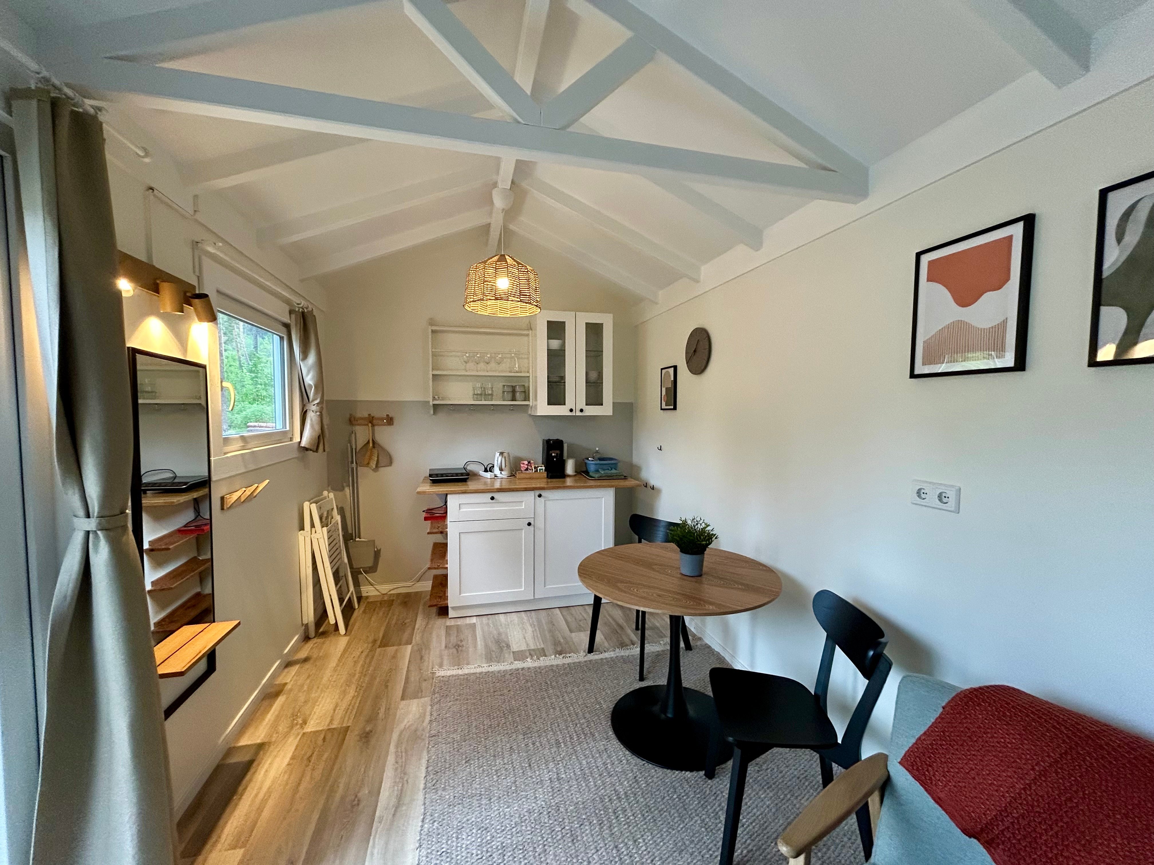 La vue intérieure d'un logement locatif montre une table, des chaises et une petite kitchenette.