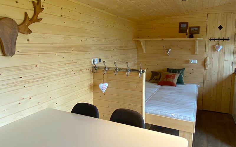 Un lit double dans un logement en bois à louer.
