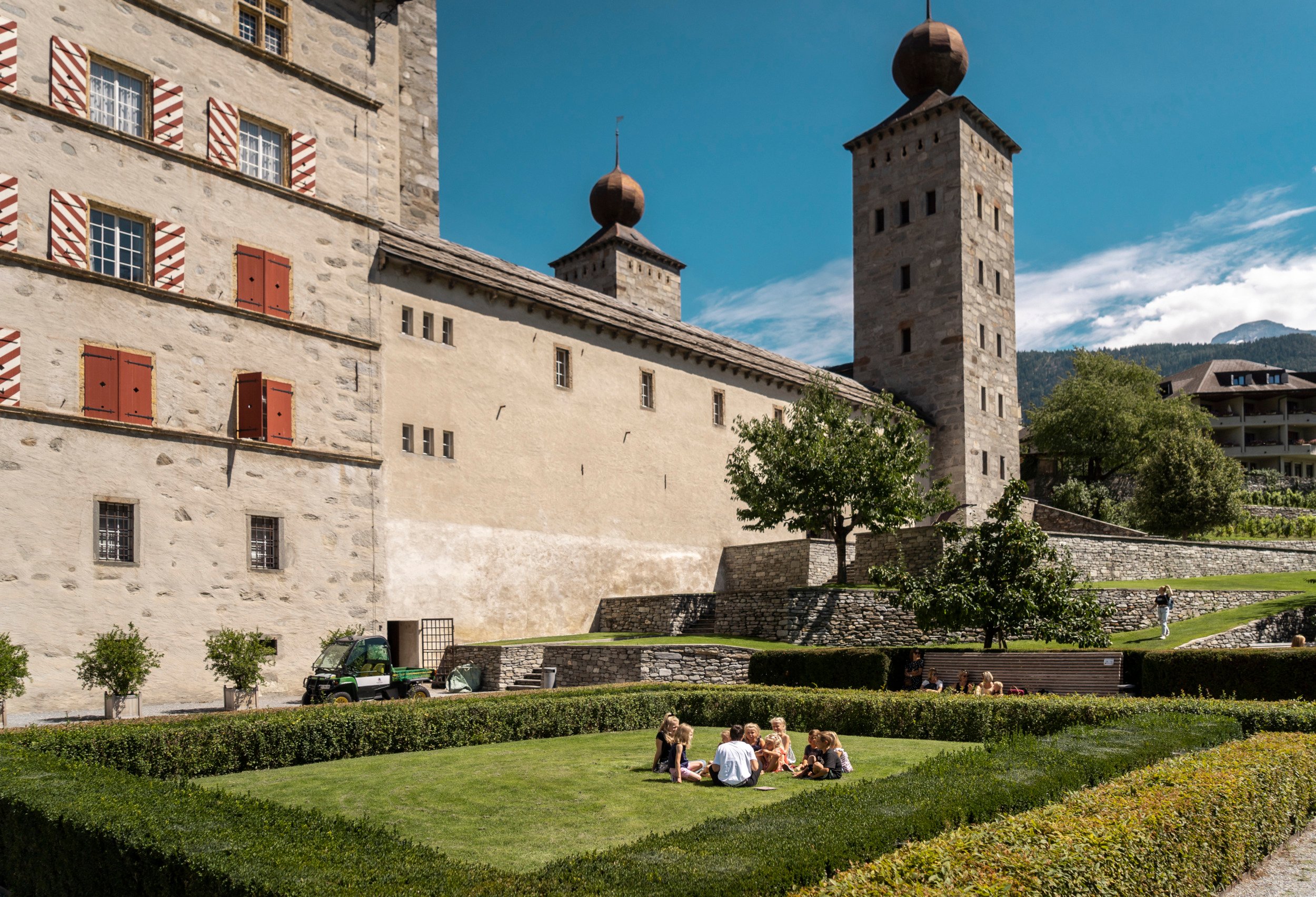 Eine Gruppe von Kindern sitzt im Garten vor dem Stockalperschloss