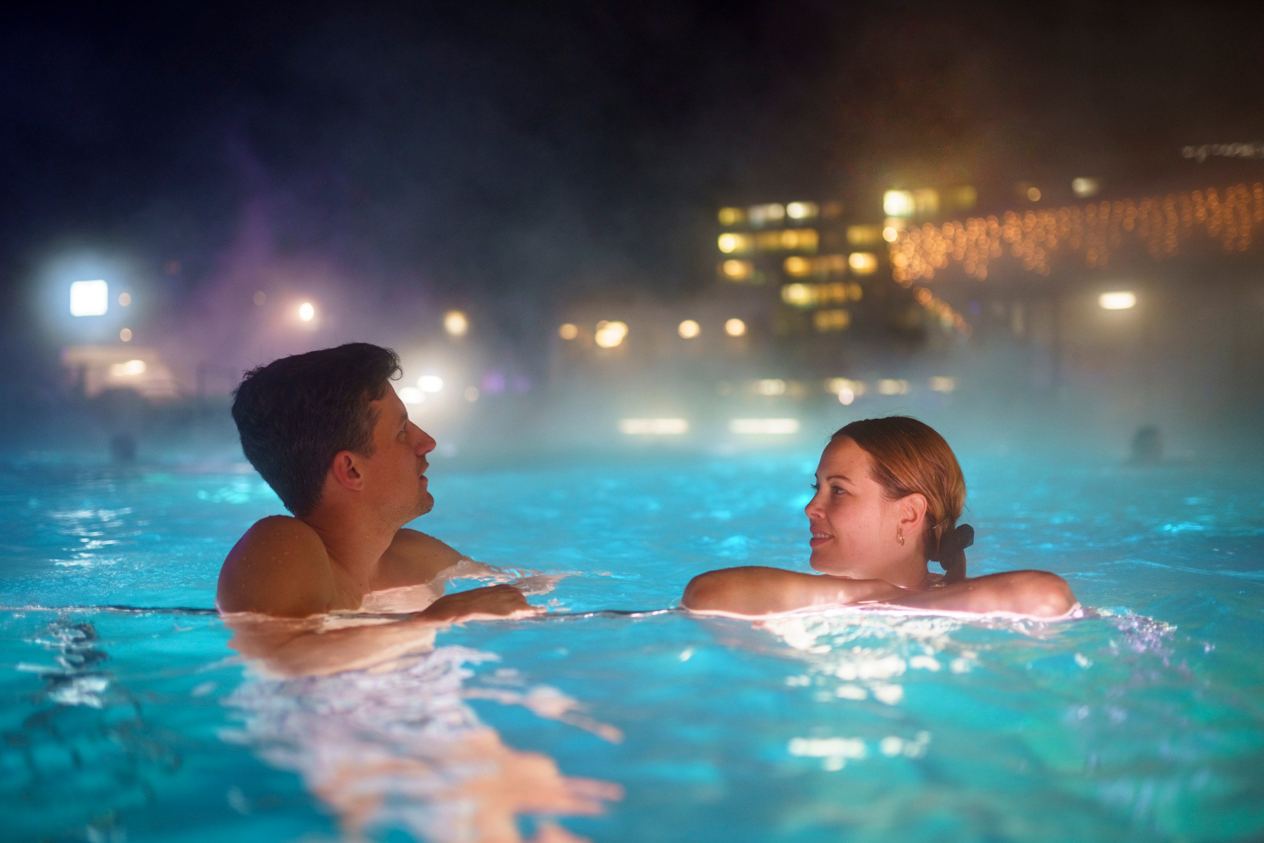 Two people relax in the outdoor area of a thermal bath.