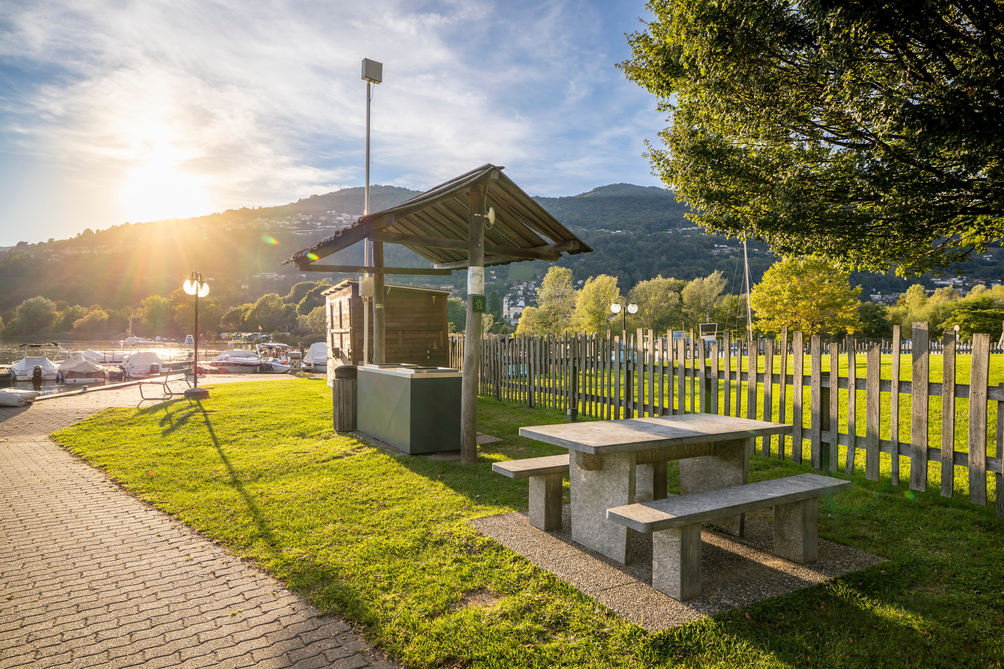 Barbecue extérieur avec table en pierre et bancs au bord du lac.