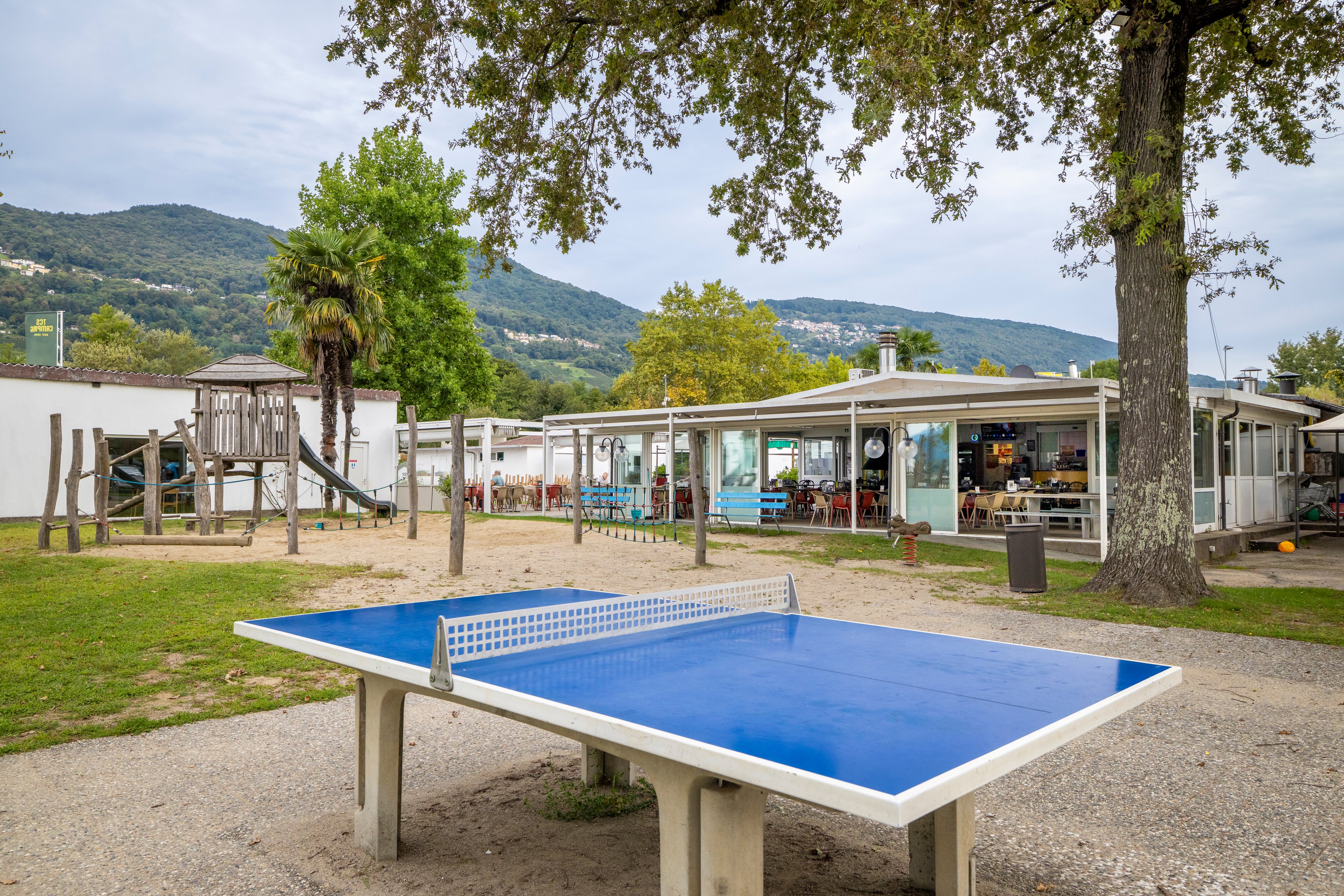 Un restaurant dans un camping avec une aire de jeux au premier plan.