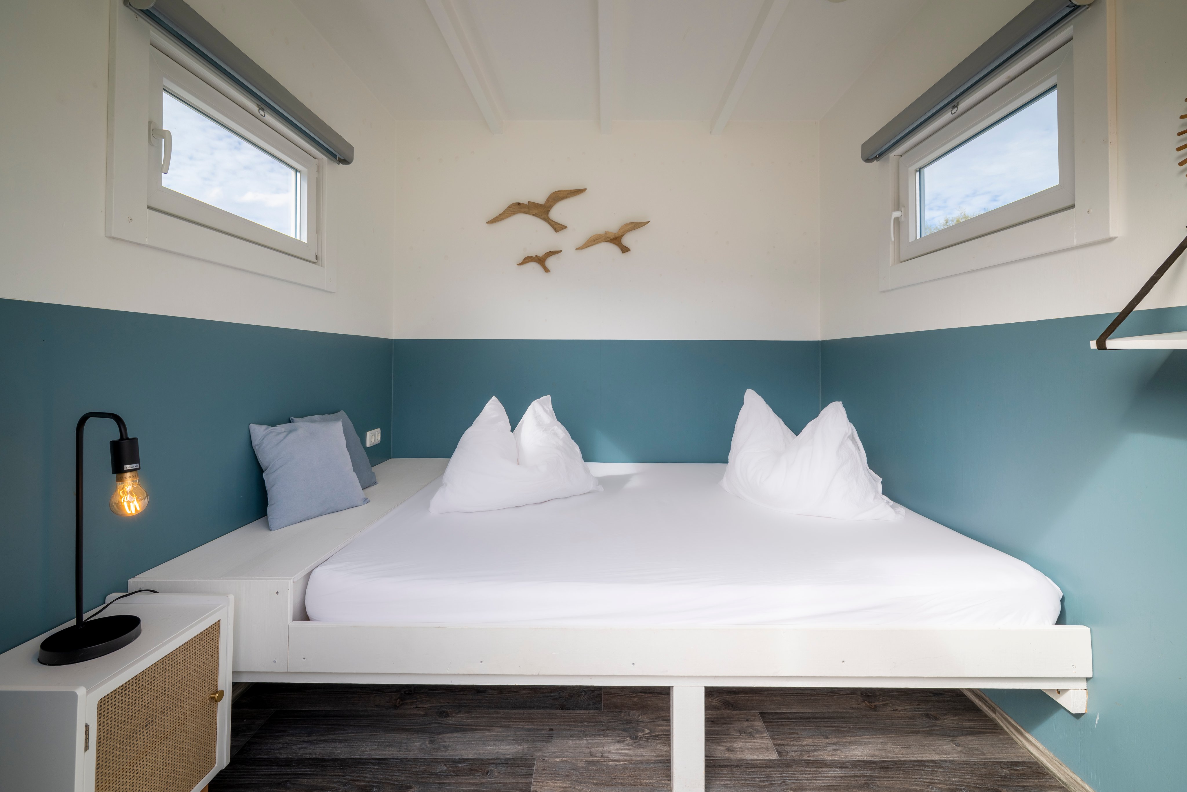 Un lit double dans un logement loué aux murs bleus et blancs.