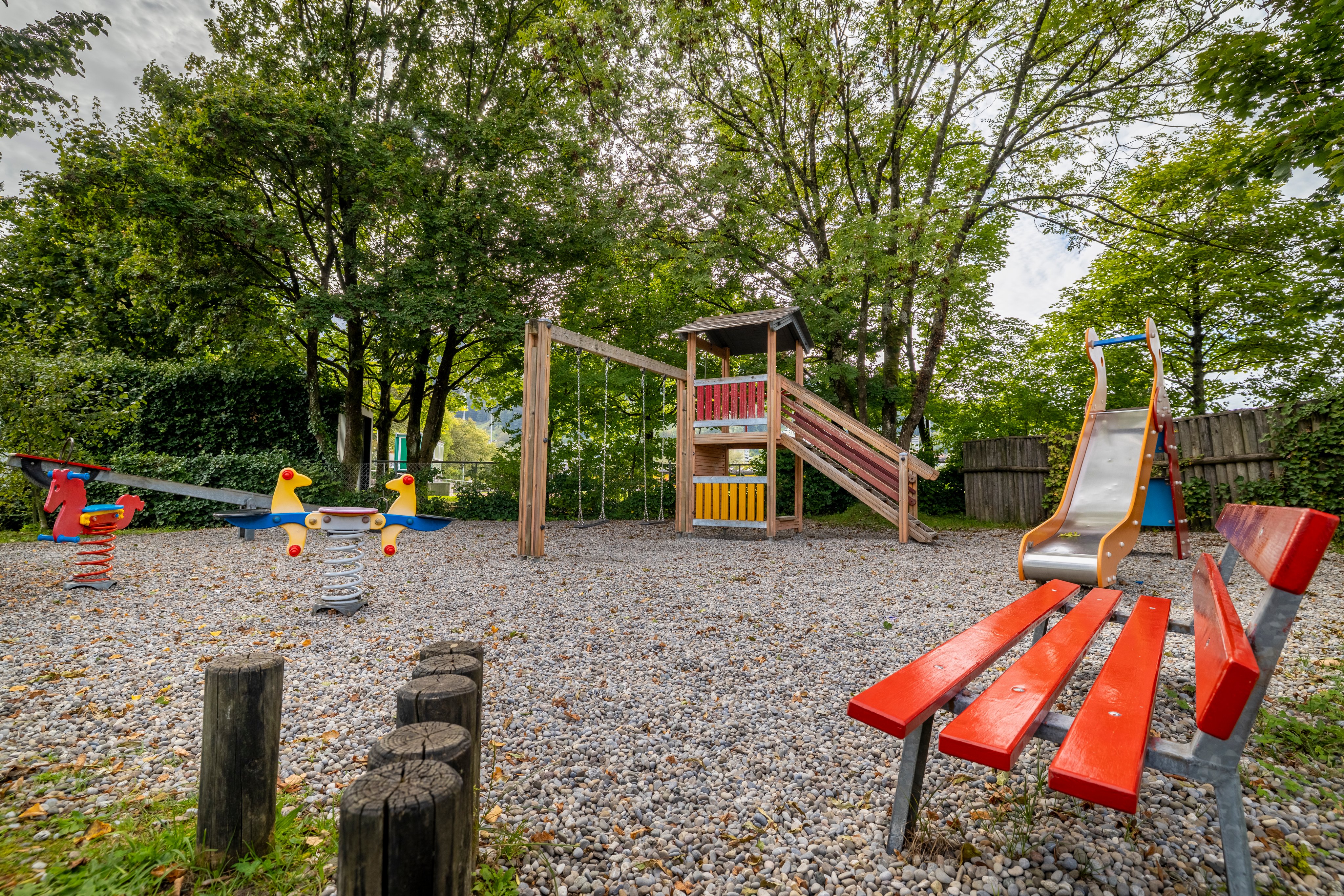 Spielplatz mit Rutsche, Klettergerüst und Schaukeln auf einem Campingplatz.