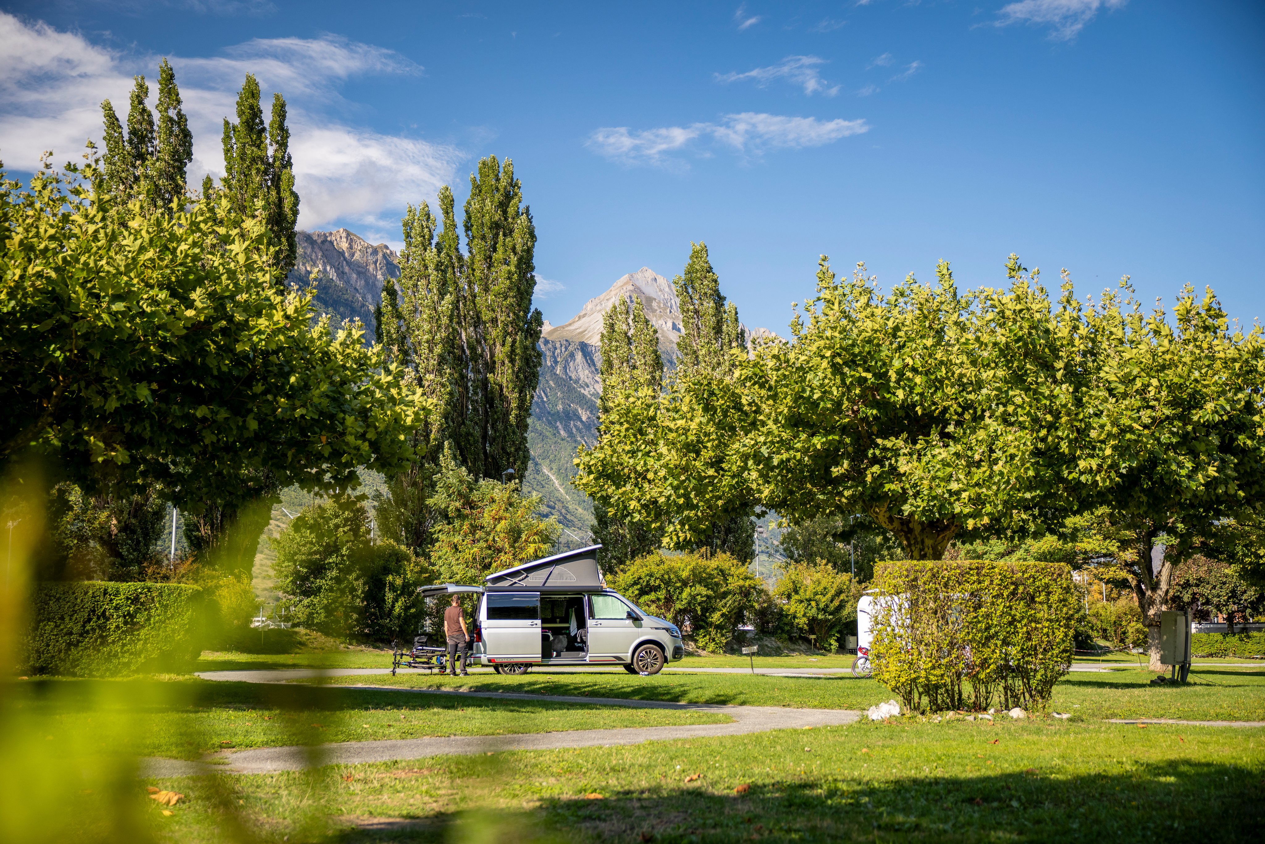 Fourgon blanc sur une place de stationnement au camping TCS Martigny.