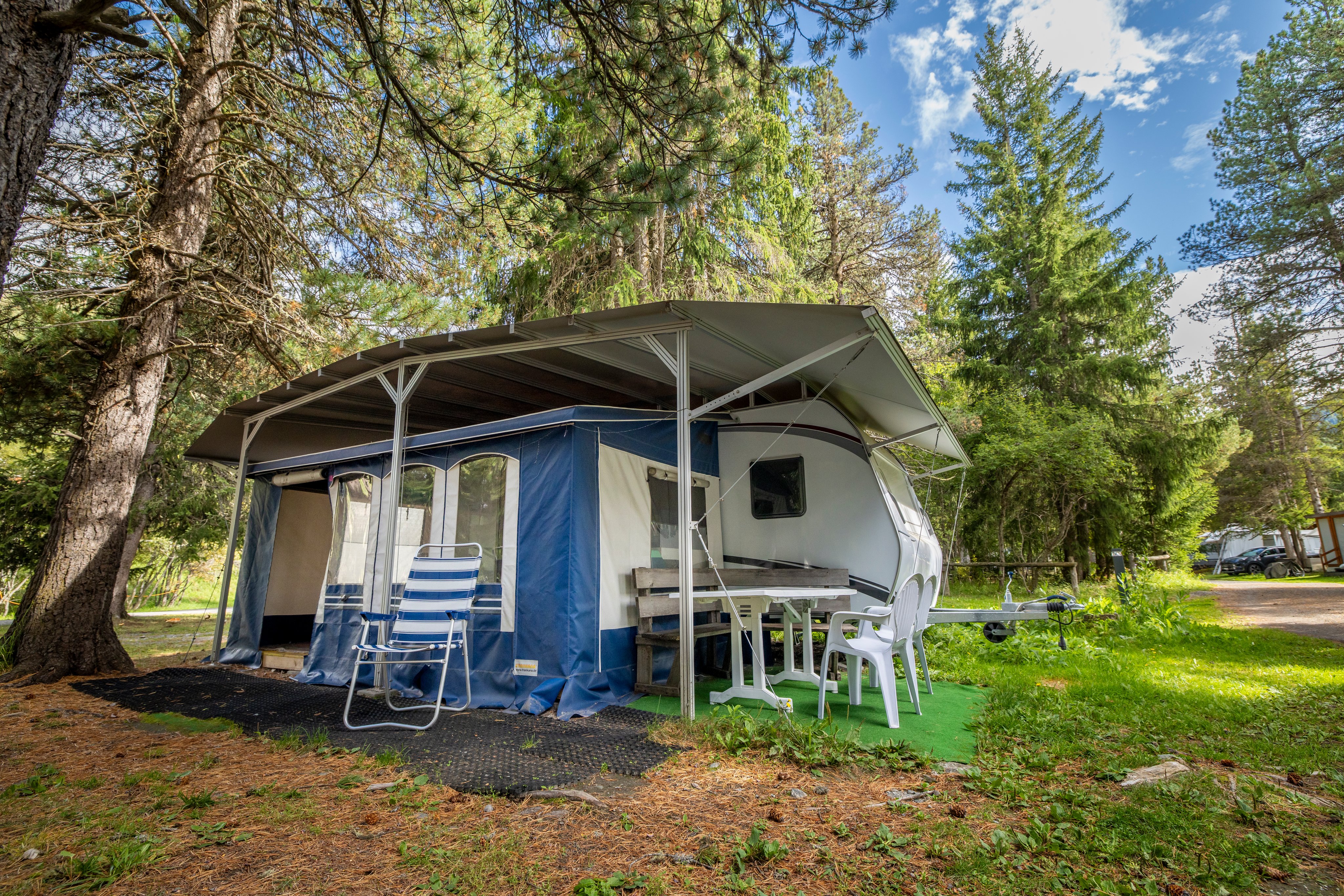 Une caravane sous les arbres dans un camping.