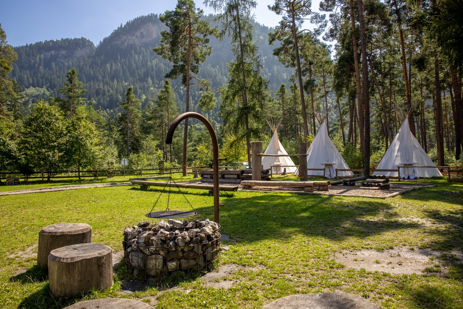 Tre tipis e un'area barbecue in un campeggio in campagna.