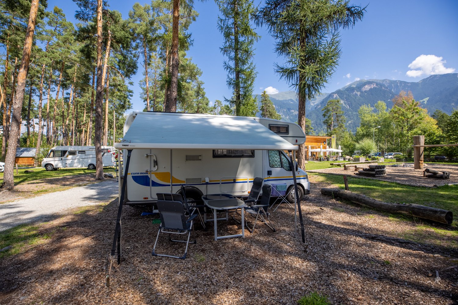 Un camper in un campeggio con sedie e tavolo.