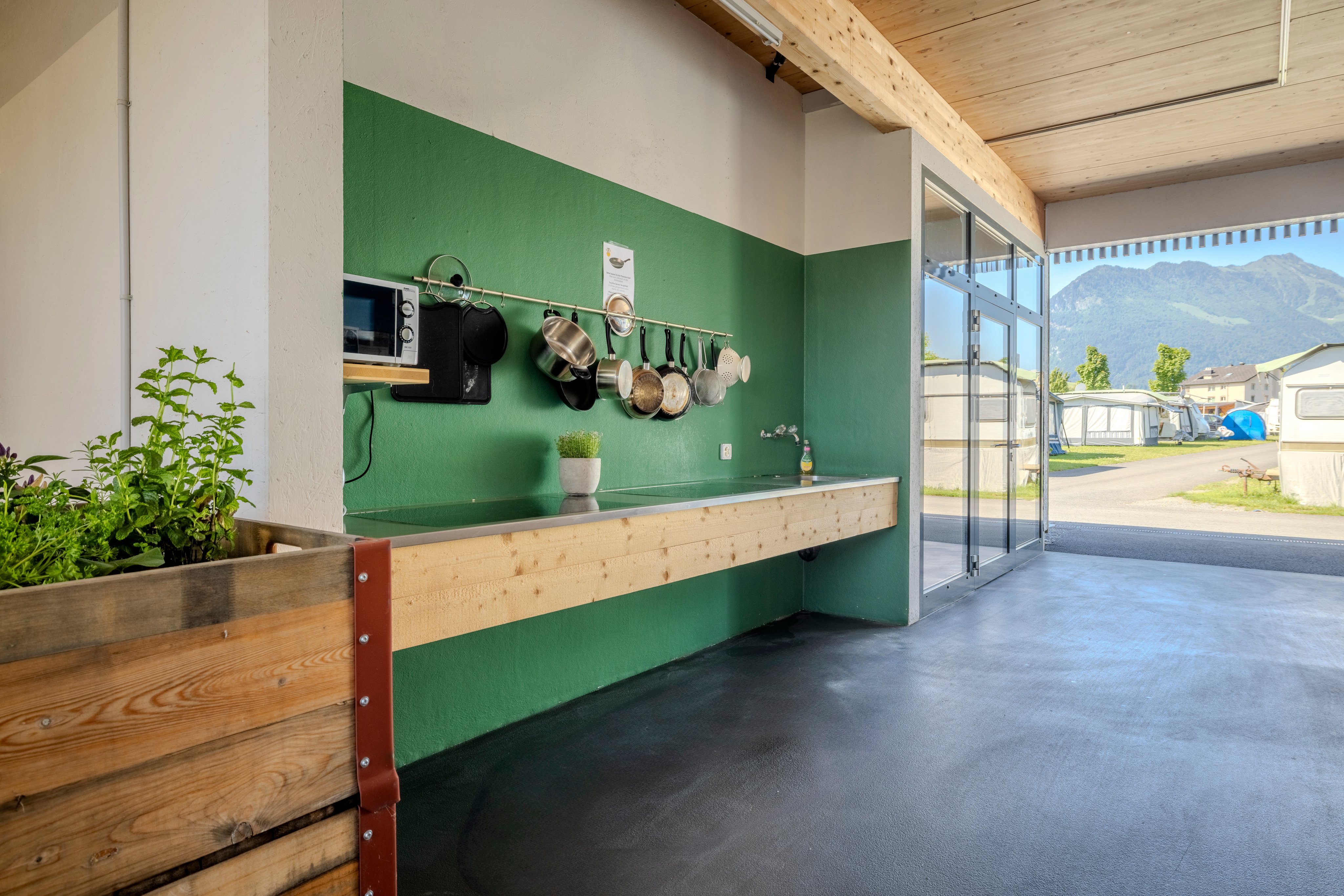 Une cuisine extérieure avec un mur vert dans un camping.