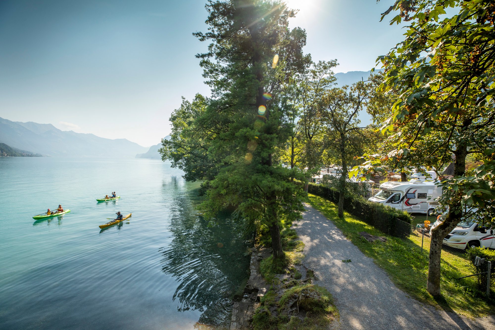Tre kayakisti sul lago vicino a un campeggio.