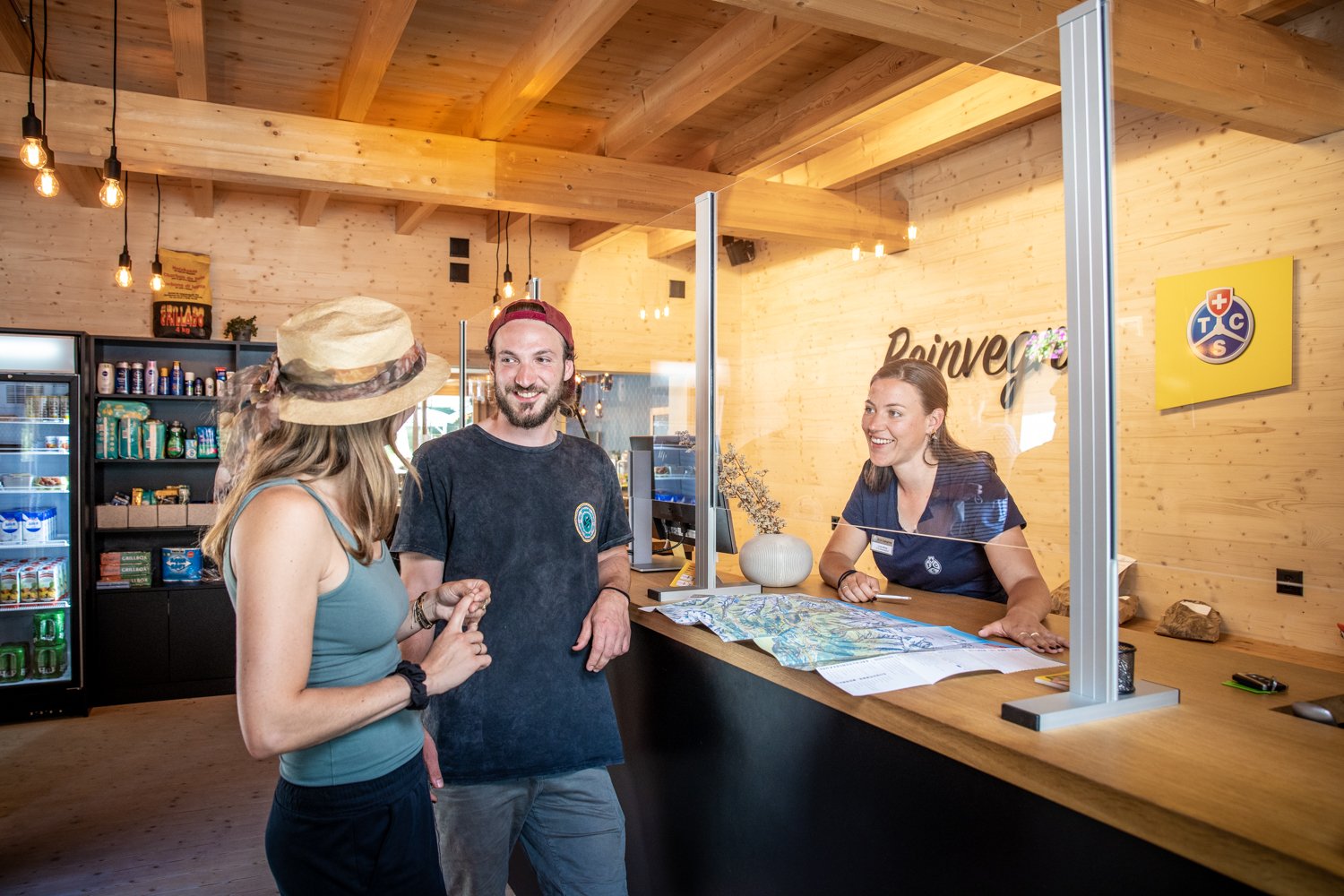 Three people at the reception of a campsite.