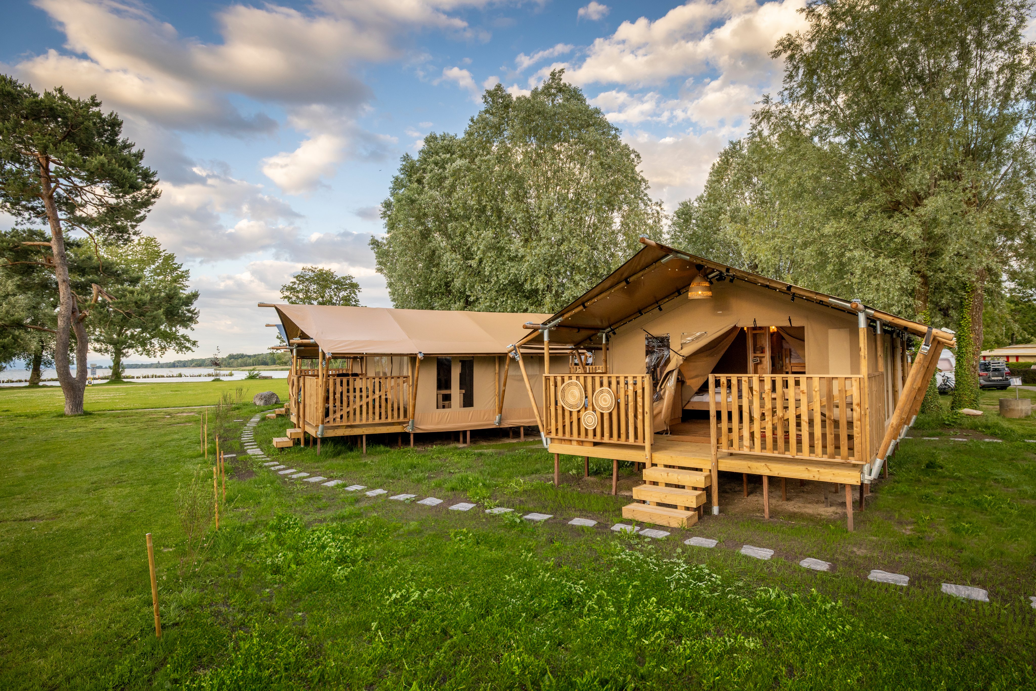 Zwei Safarizelte auf einem Campingplatz an einem See. 