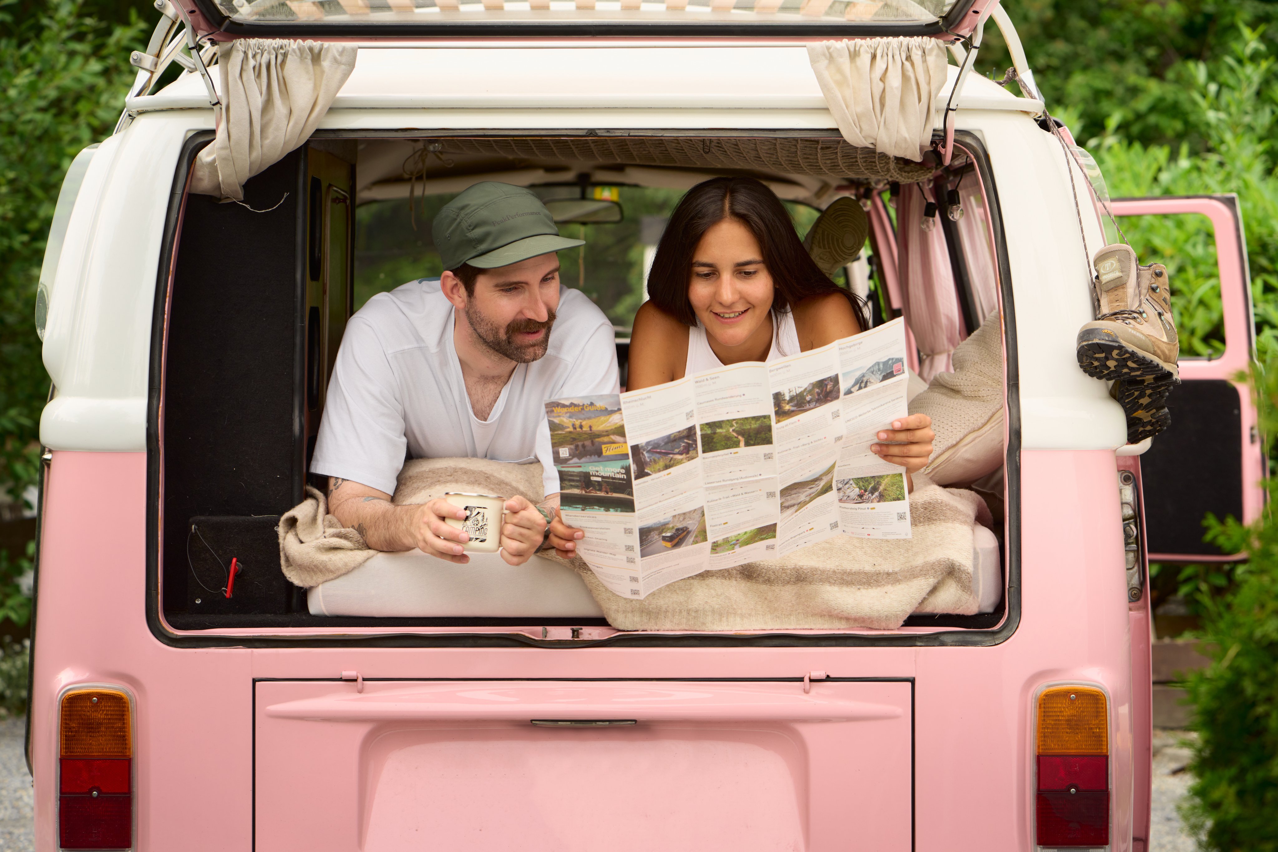 Une femme et un homme étudient ensemble une carte de randonnée dans une camionnette.