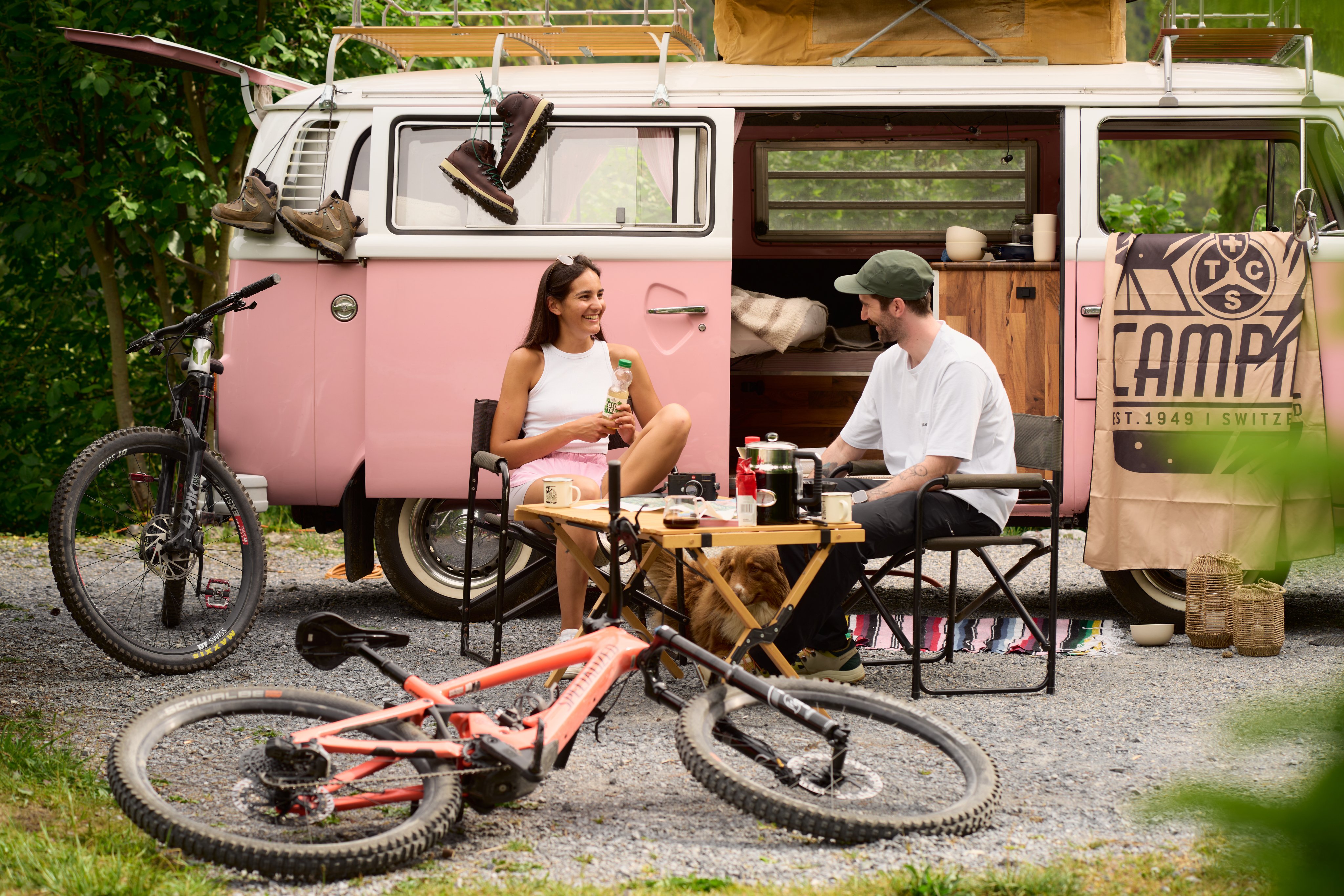 Due persone che bevono un caffè davanti a un camper del TCS Camping Flims