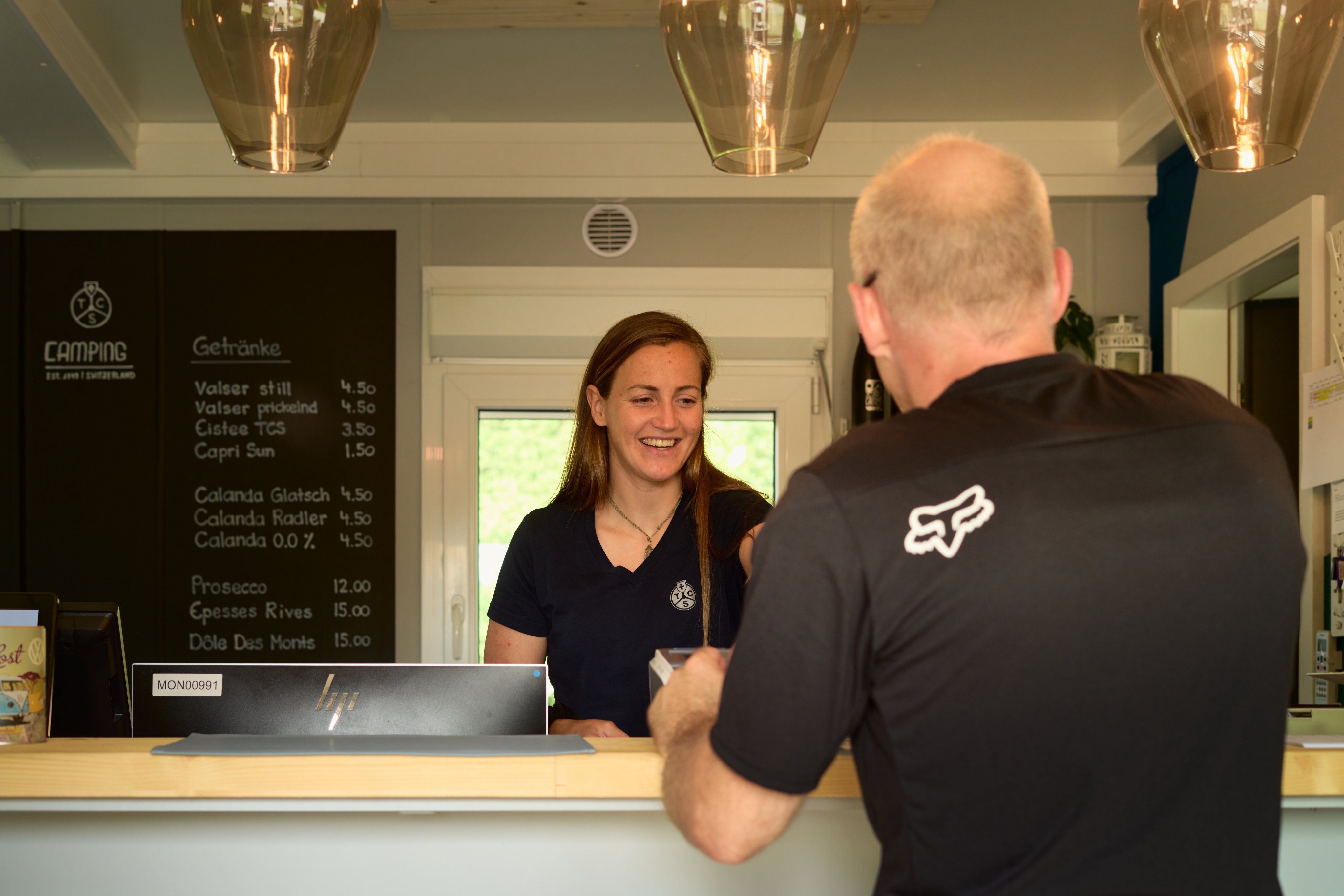 Zwei Personen stehen an einer Rezeption auf einem Campingplatz.