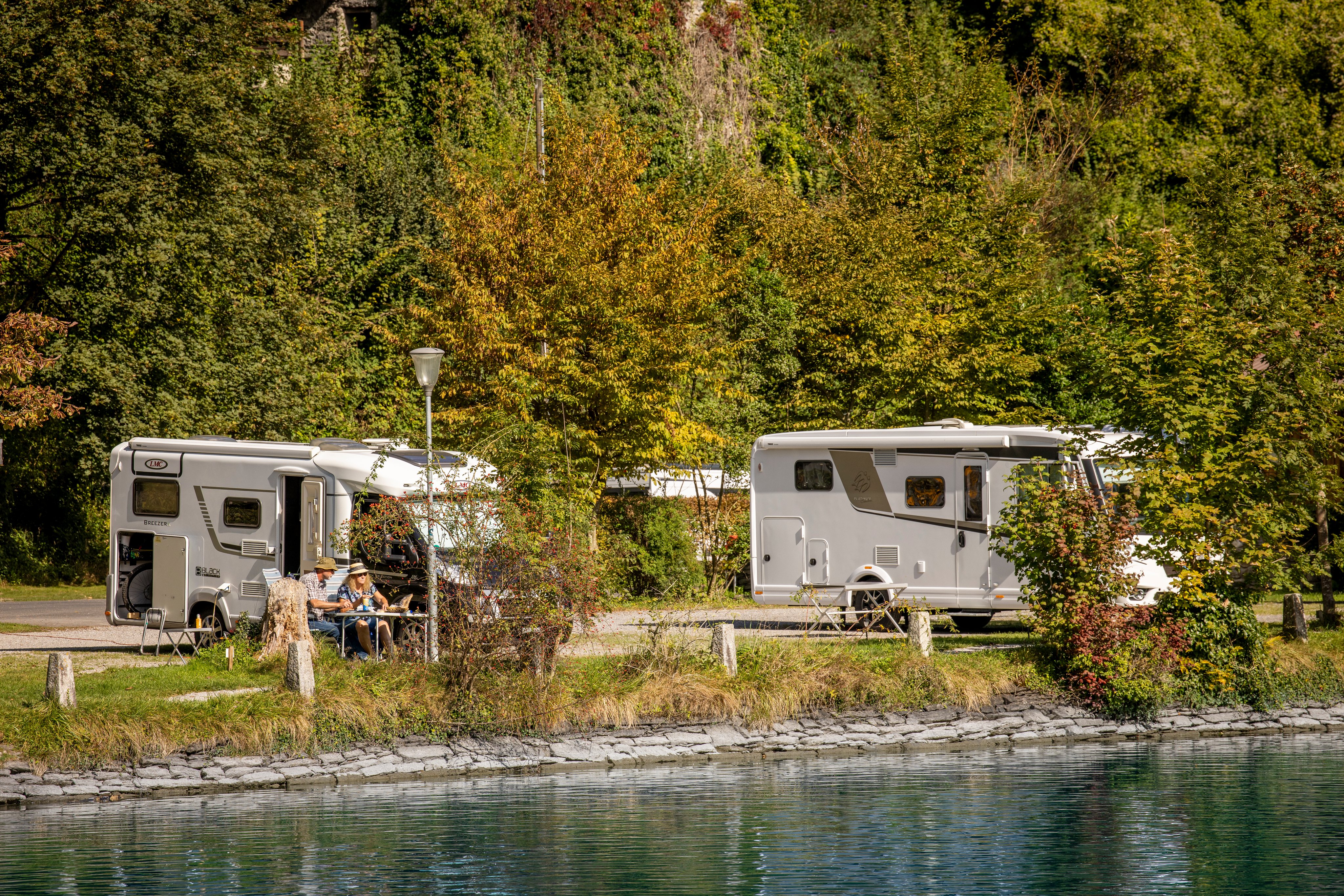 Two mobile homes on a campsite by the river.