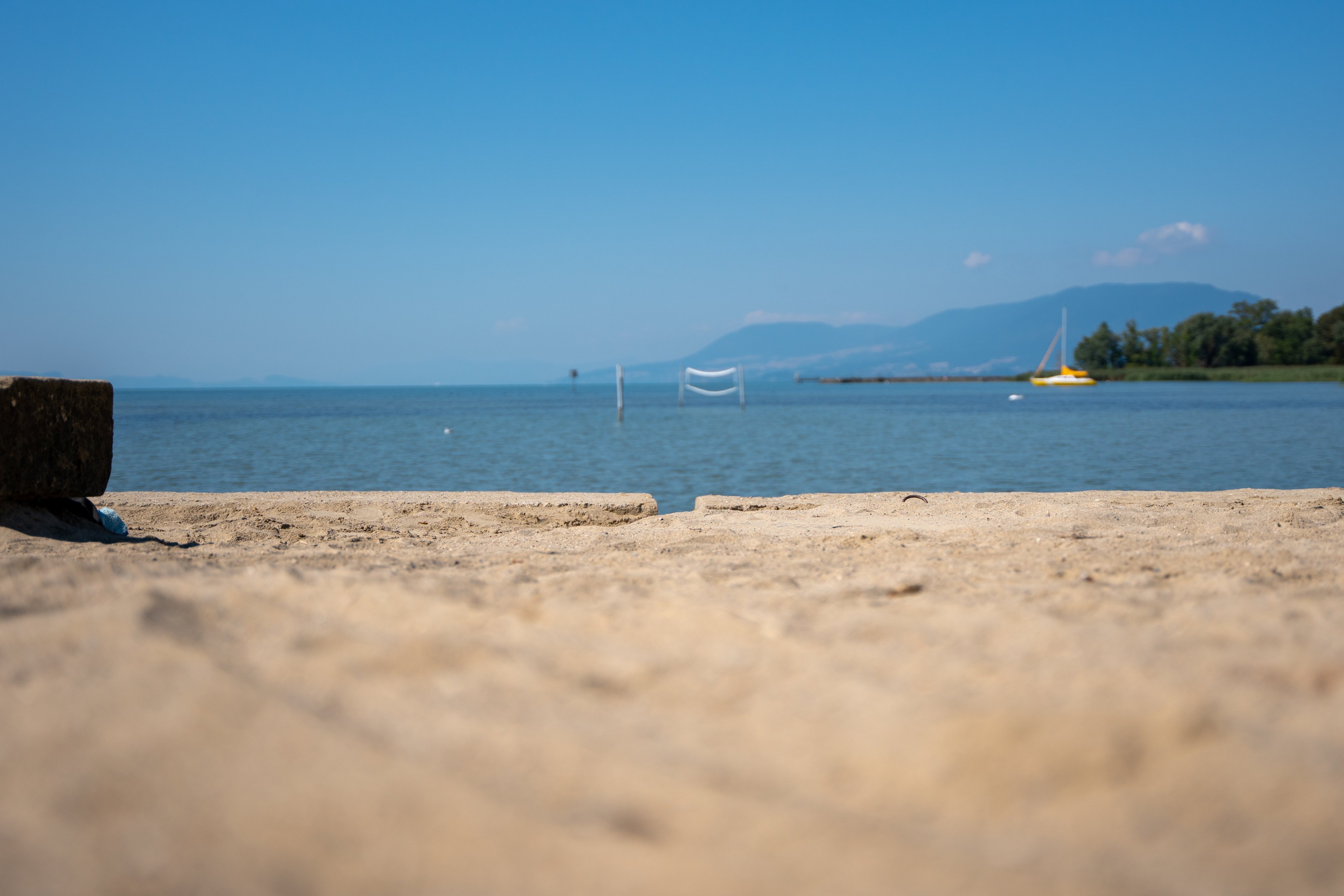 Spiaggia sabbiosa in riva a un lago, con una barca alle spalle.