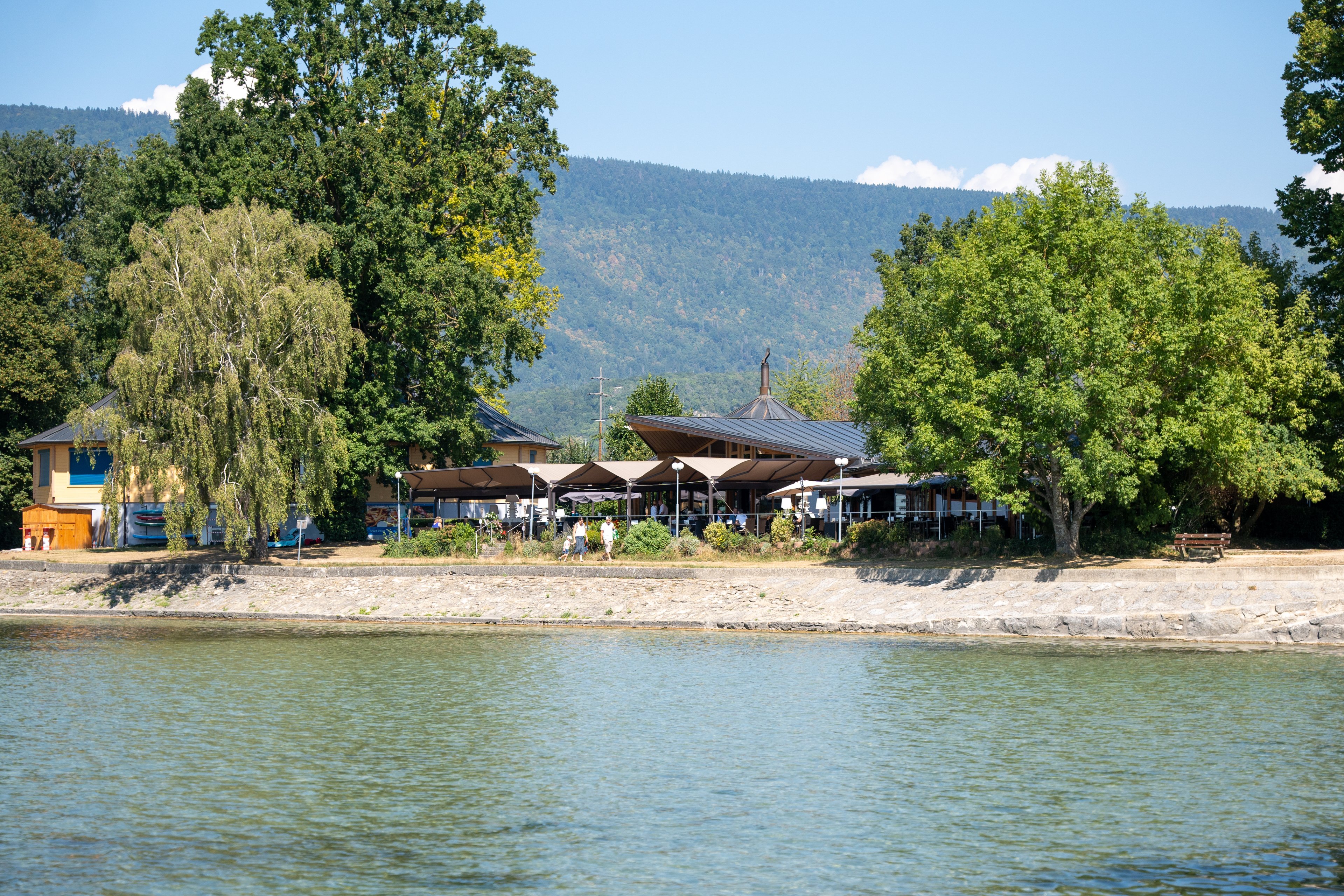 La rive d'un lac avec une terrasse en arrière-plan.