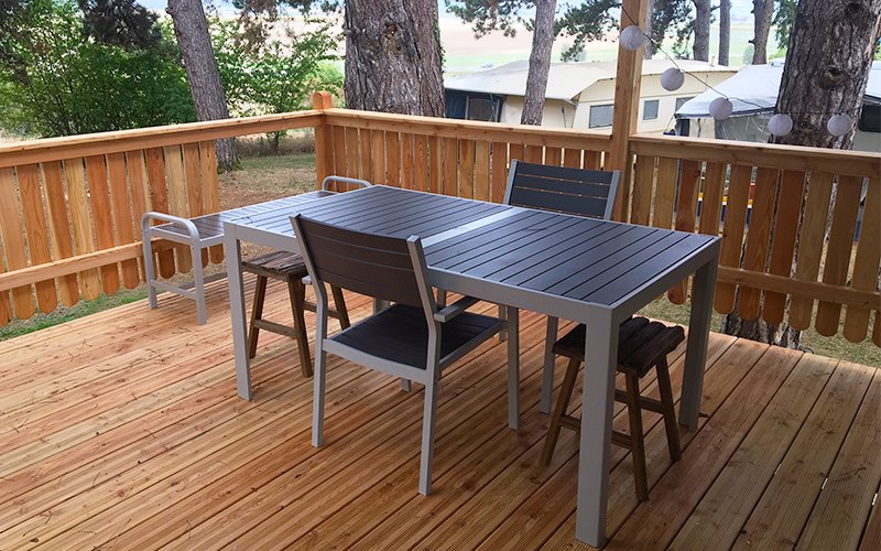 Terrasse d'un logement locatif dans un camping, équipée d'une table et de chaises.