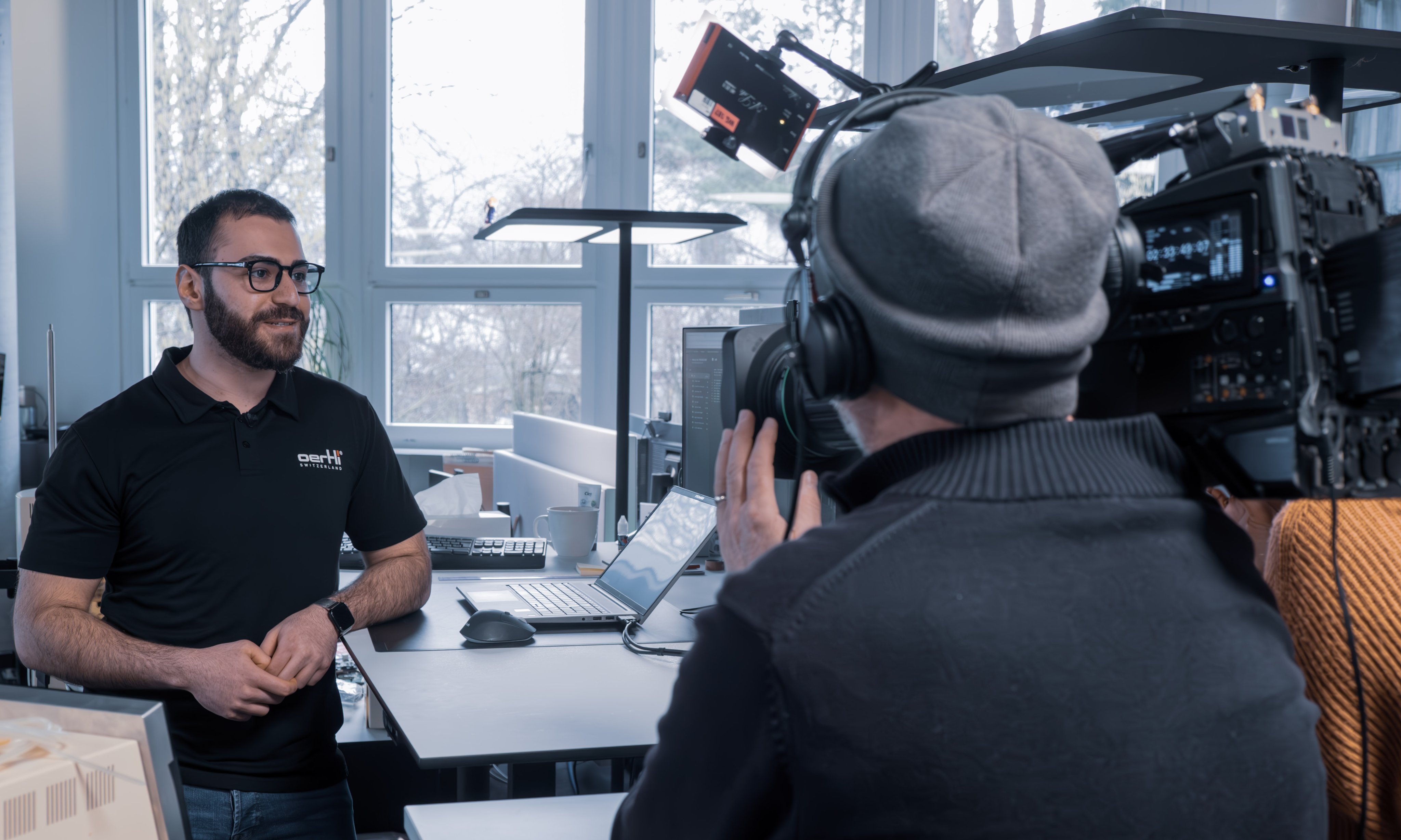 Kamerateam filmt einen Mitarbeitenden in einem Büro während eines Interviews