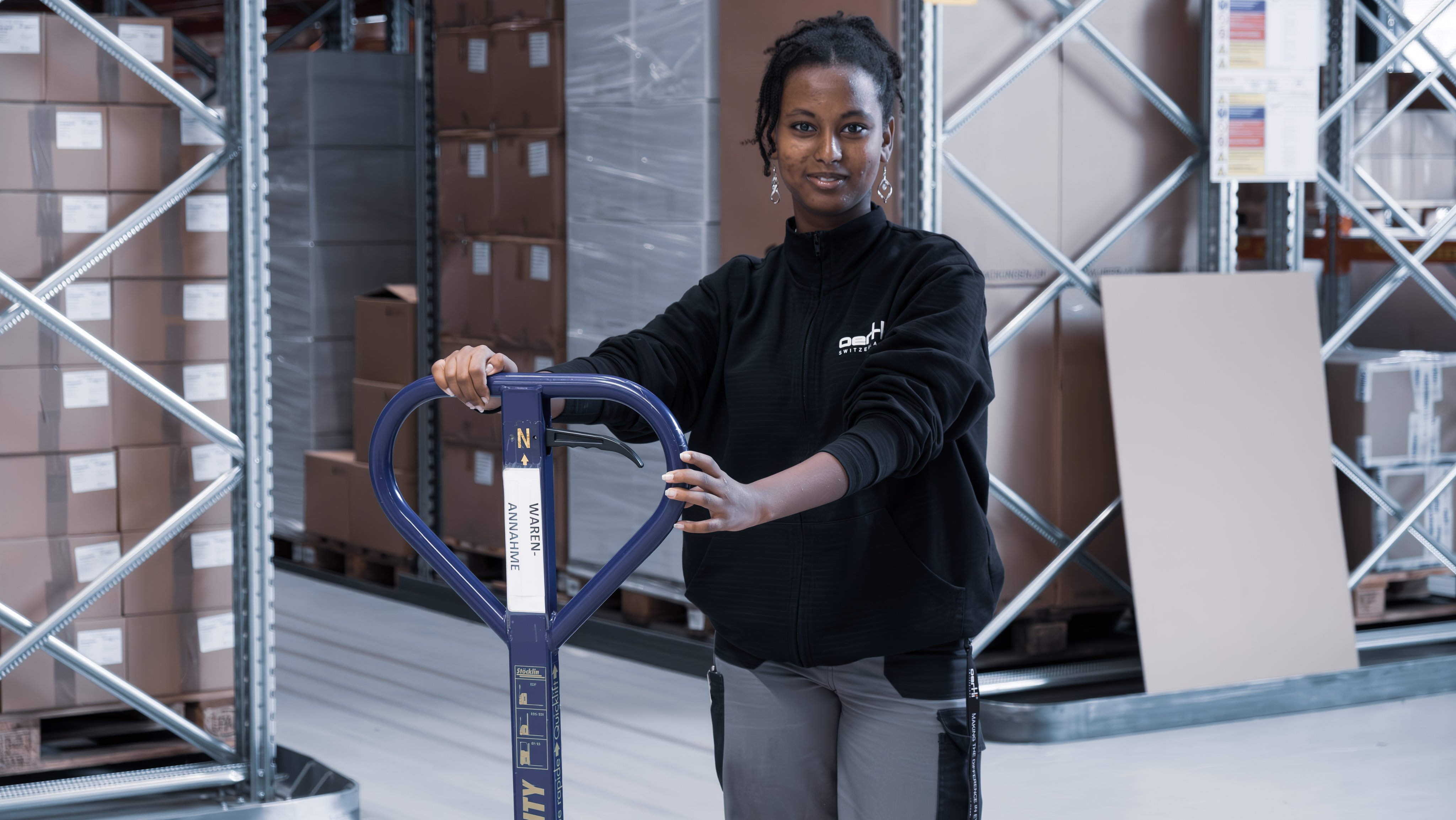 Lehrling arbeitet im Lager mit einem Transportgerät