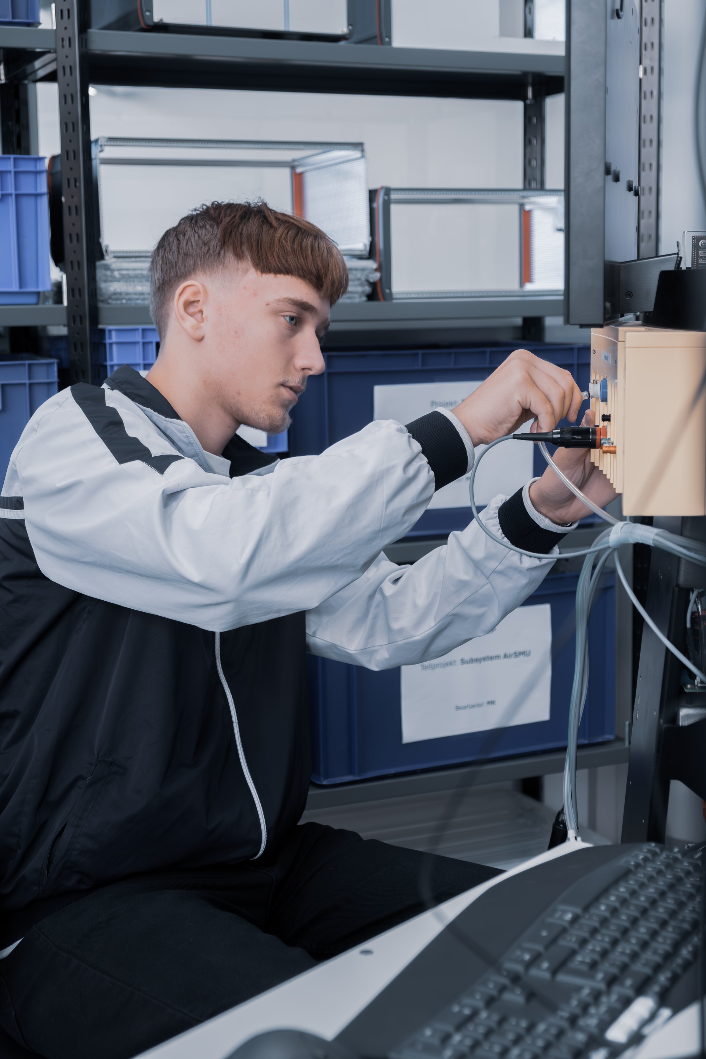 Lehrling arbeitet an elektronischen Anschlüssen an einem technischen Gerät