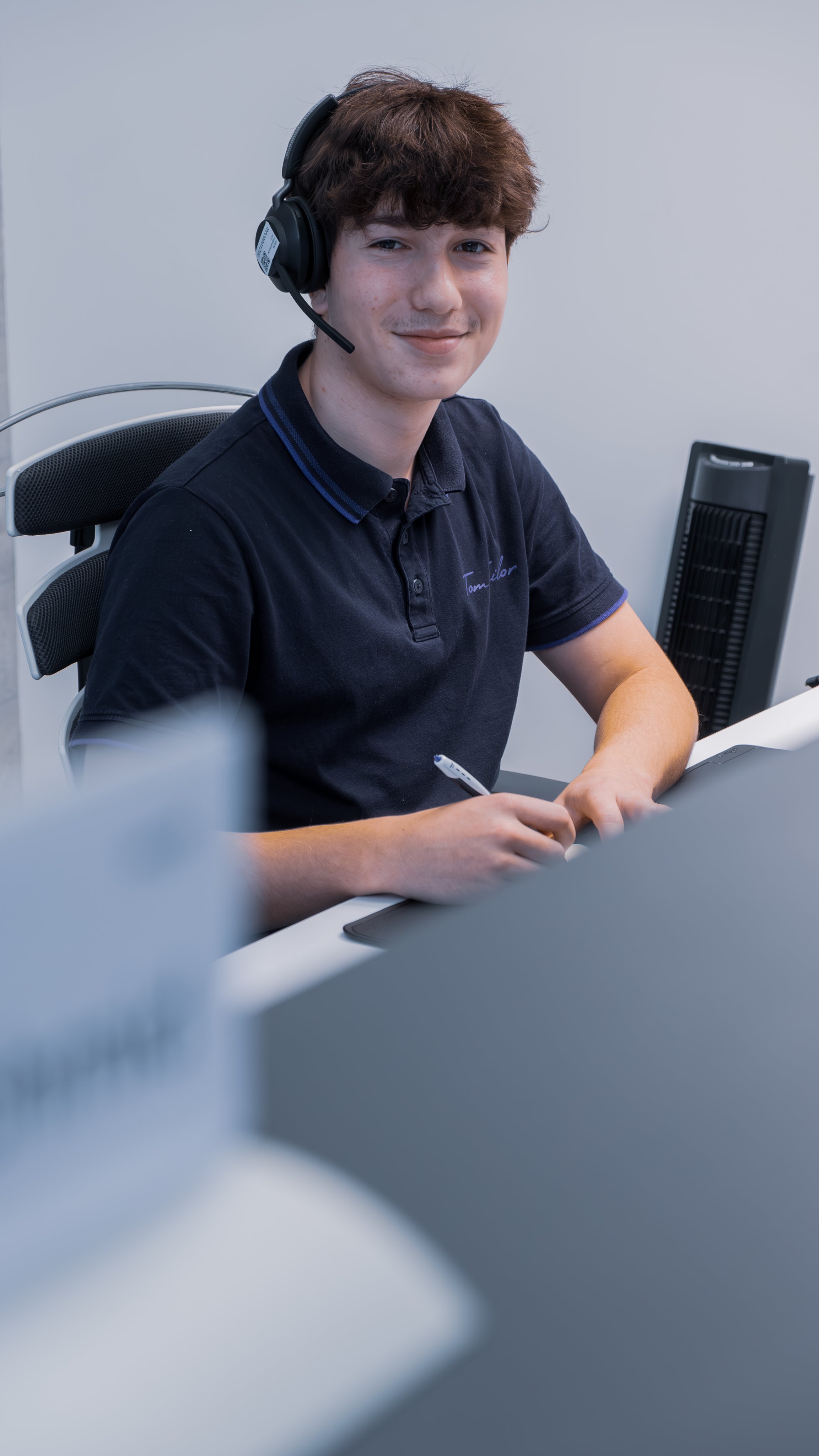 Mitarbeitender mit Headset sitzt am Arbeitsplatz im Büro