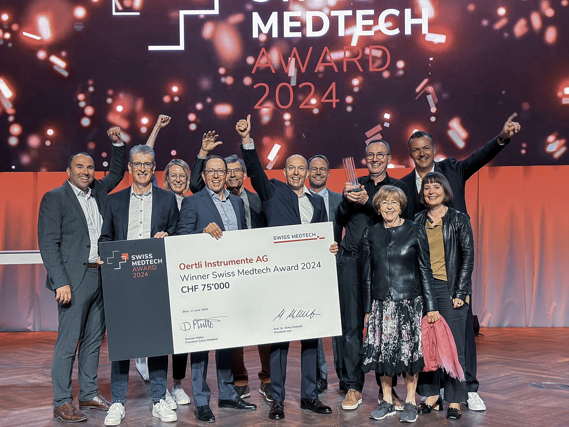 Oertli team celebrating the Swiss Medtech Award 2024 on stage with trophy and award cheque