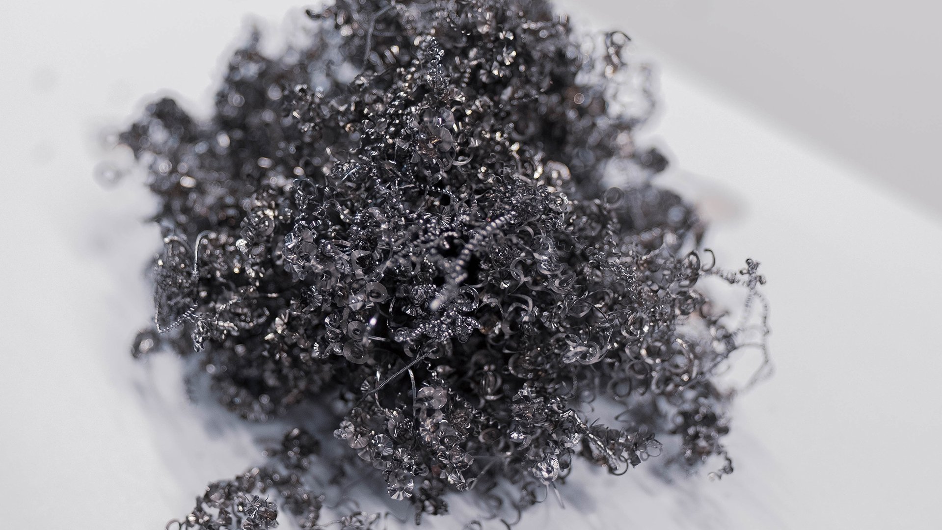 Macro view of metallic titanium shavings from industrial manufacturing on a white surface.