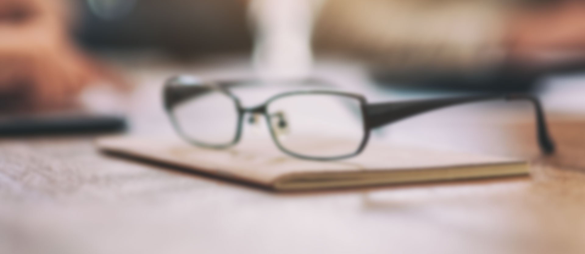 Close up of eyeglasses resting on a notebook with a blurred background, representing vision correction and eye care