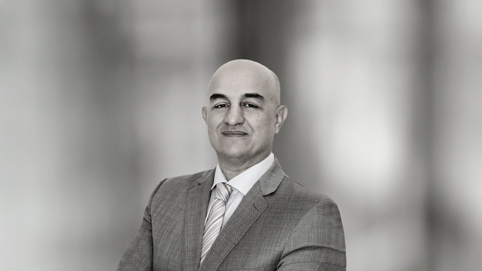 Portrait of Dr Qasim Qasem smiling, wearing a suit and tie