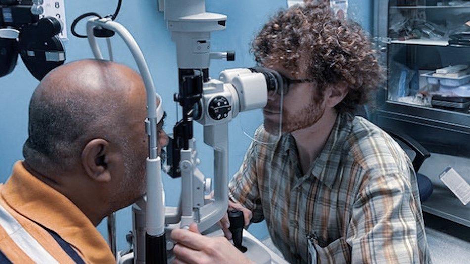 Eye care professional examining a patient with a slit lamp microscope during a clinical eye examination