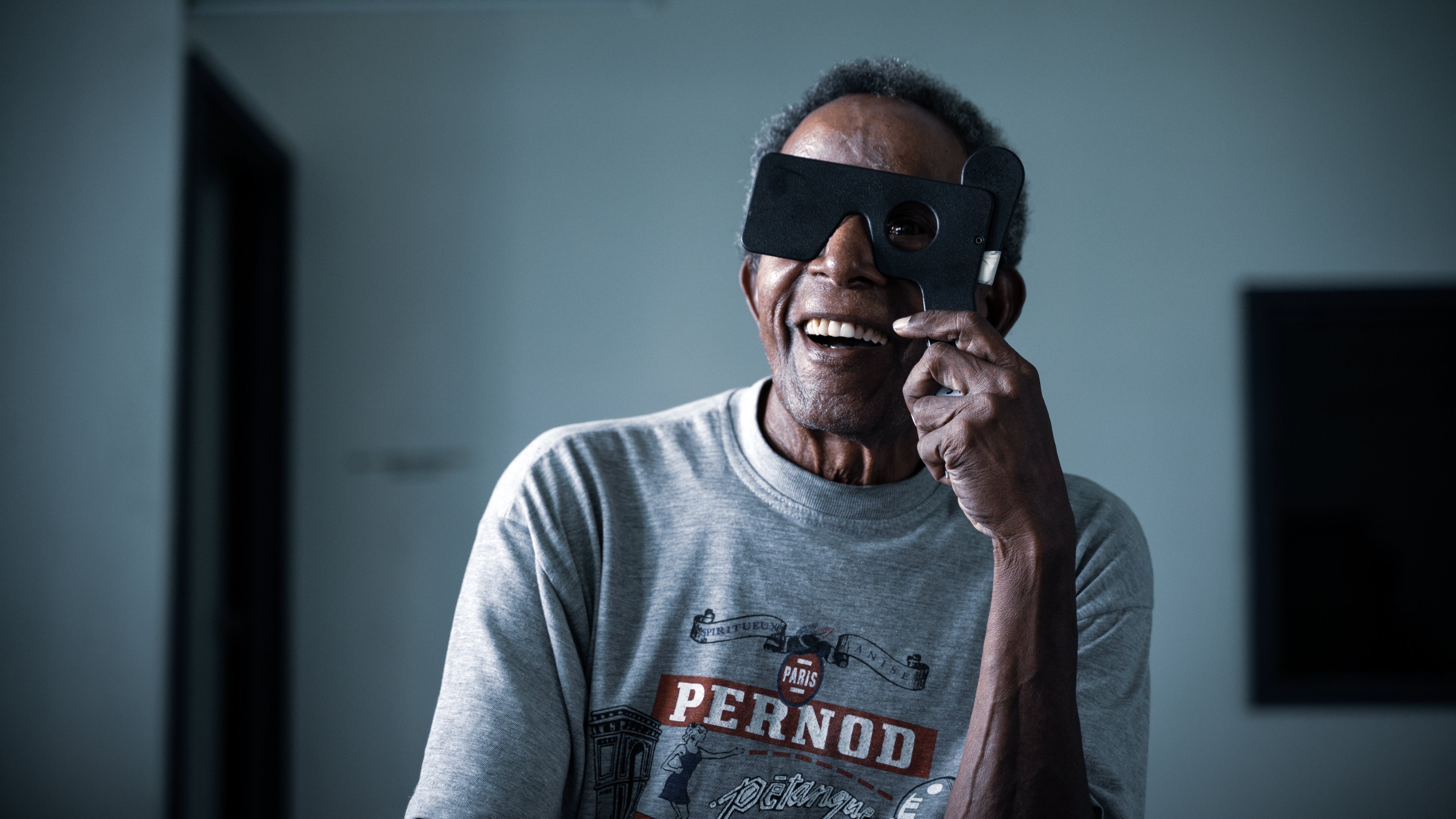 Smiling participant holding an eye screening occluder during a vision assessment