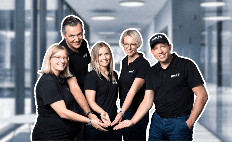 Oertli marketing and sales team posing together with the #oertlispirit graphic in a hallway setting