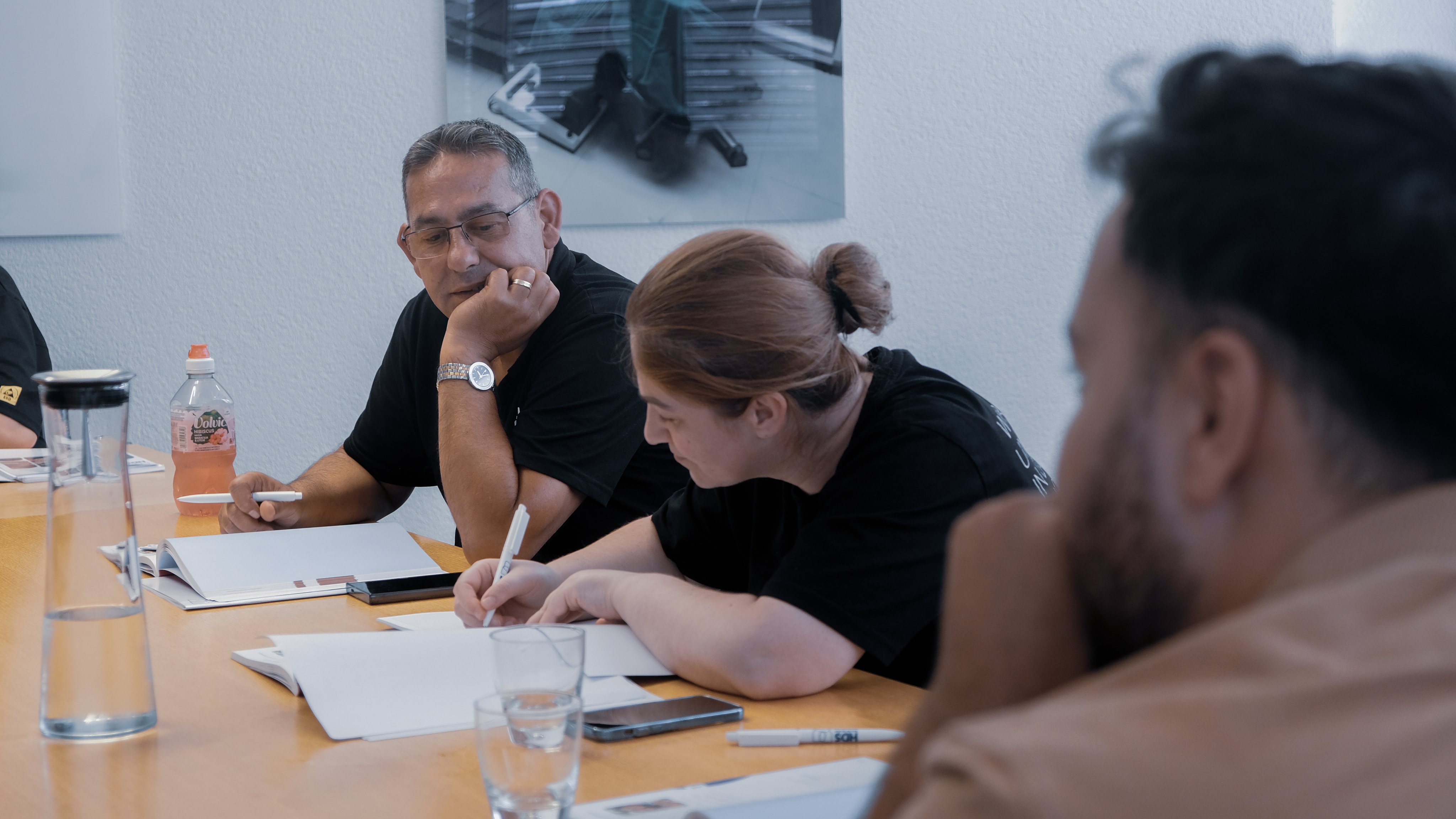 Oertli Mitarbeitende sitzen in einem Deutschkurs an einem Tisch, machen Notizen und tauschen sich gemeinsam aus