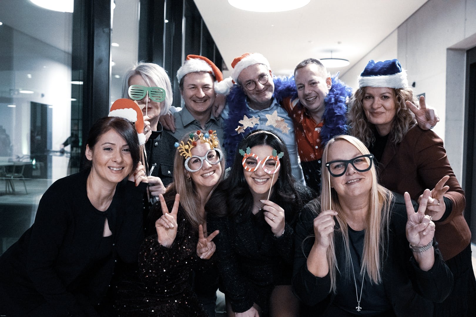Oertli Mitarbeitende posieren bei der Weihnachtsfeier mit festlichen Accessoires und lächeln in die Kamera
