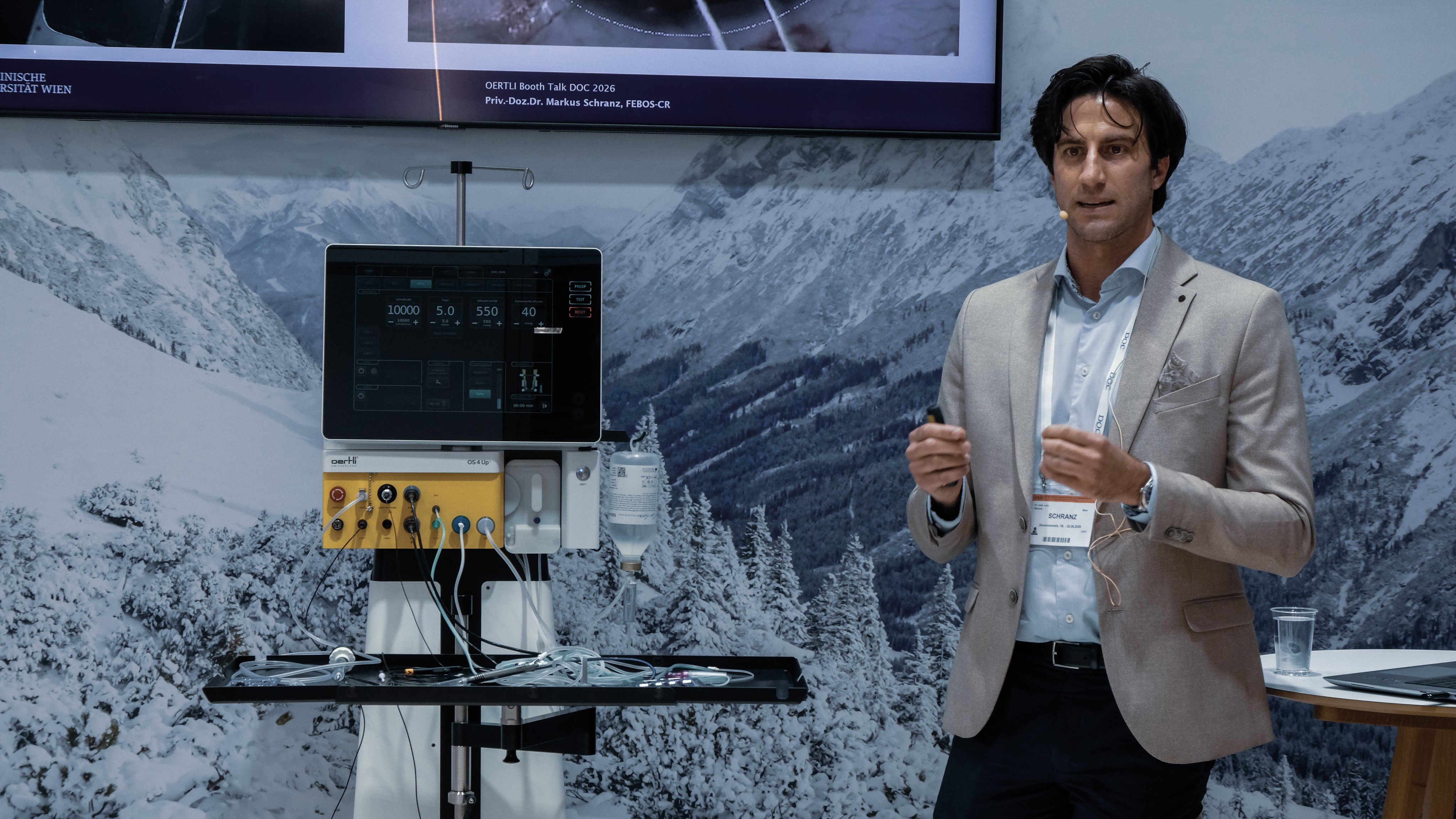 Ophthalmologist giving a booth talk beside the OS 4 Up surgical platform at an exhibition