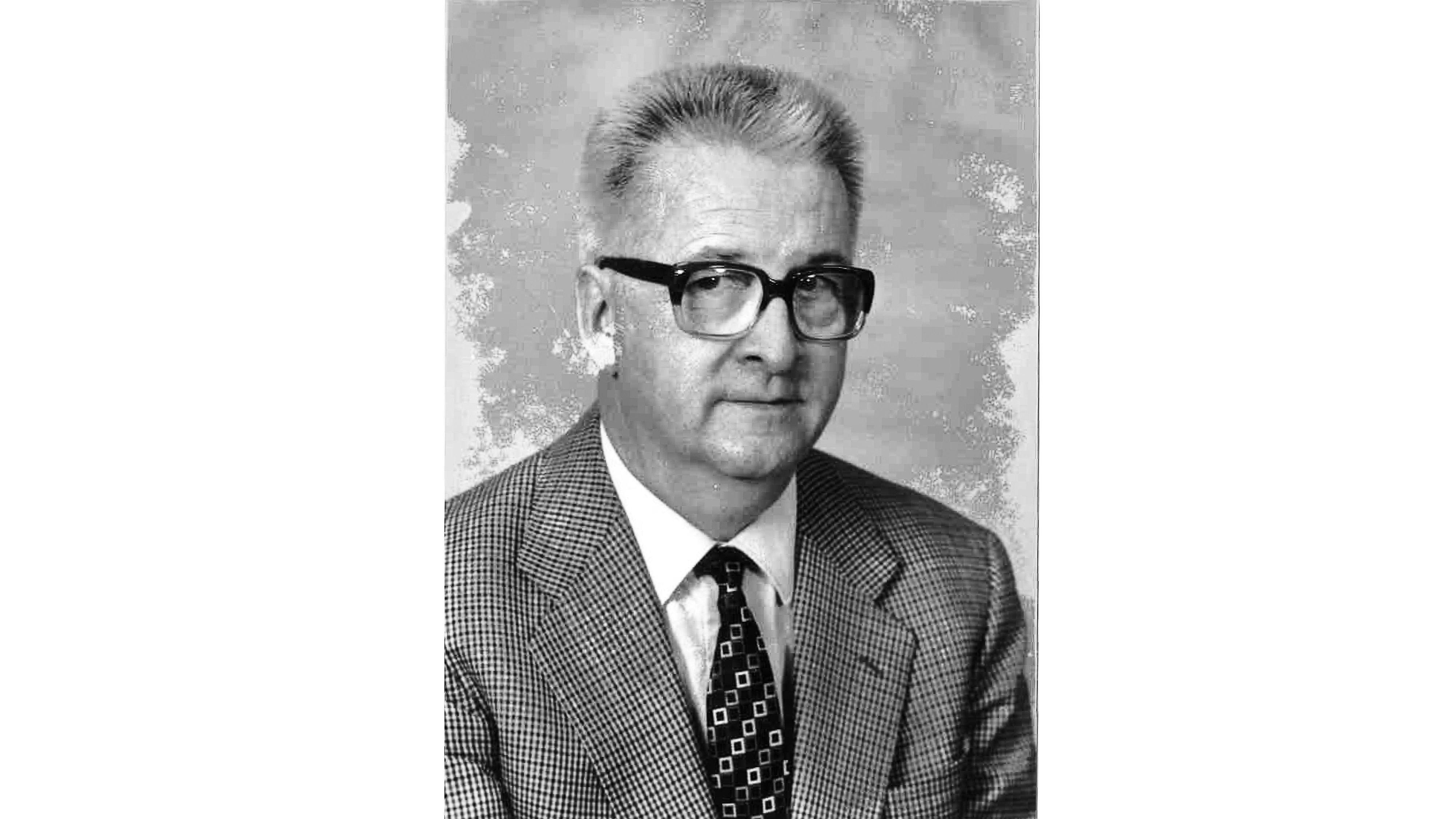 Black-and-white portrait of prof kloeti wearing glasses, a checked jacket and a tie
