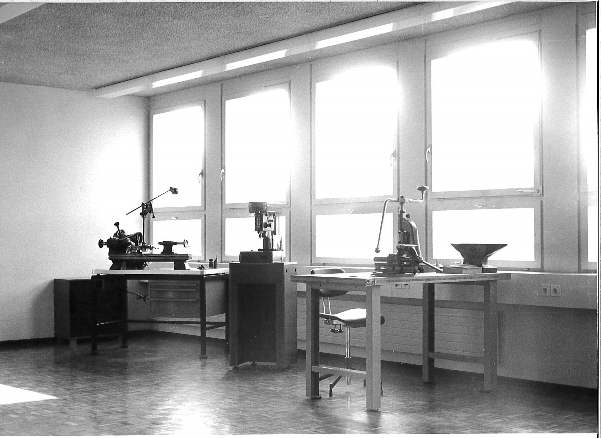 Black-and-white image of an early workshop with workbenches and technical equipment