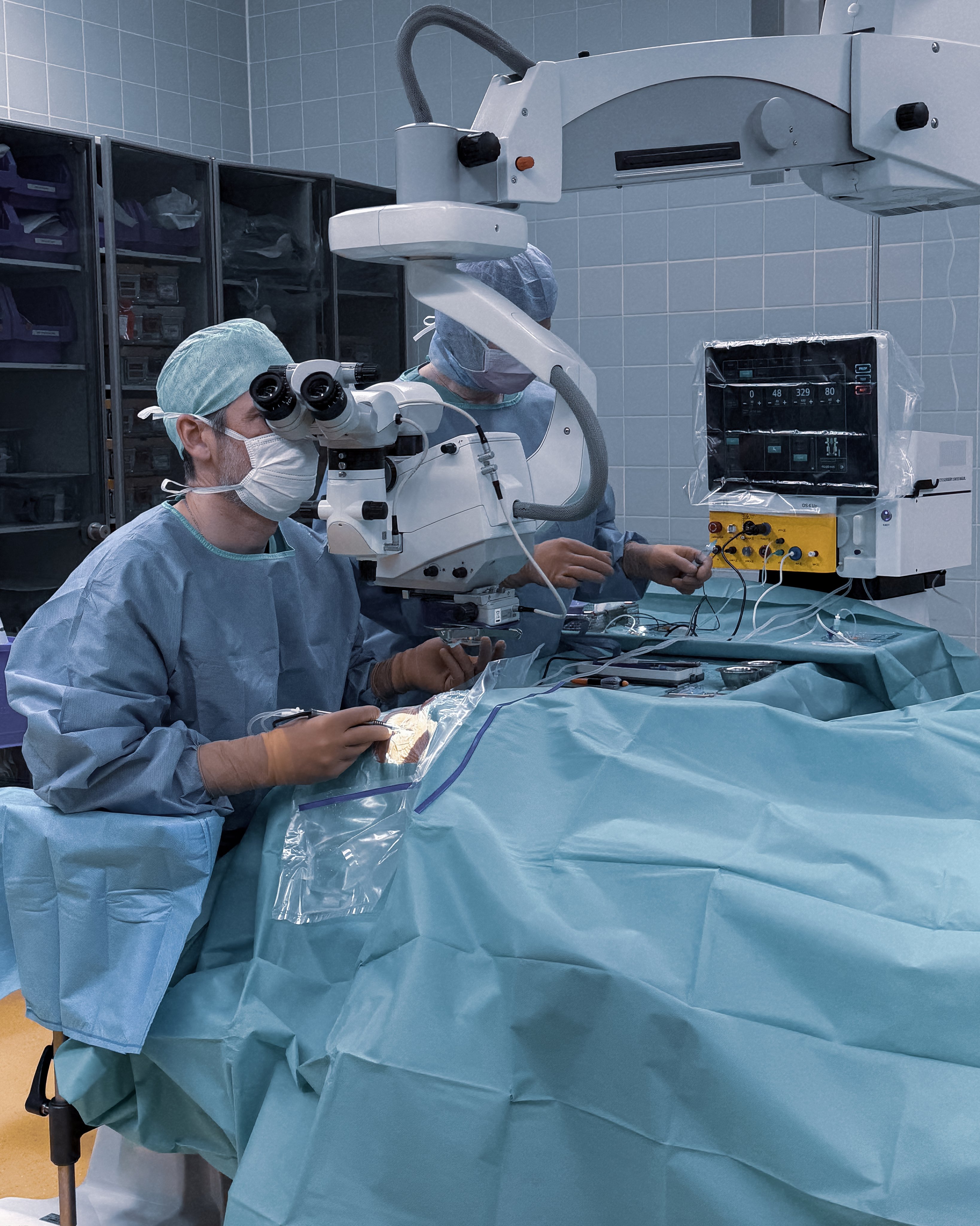 Surgeon performing an ophthalmic procedure with a microscope and Oertli surgical platform in an operating room