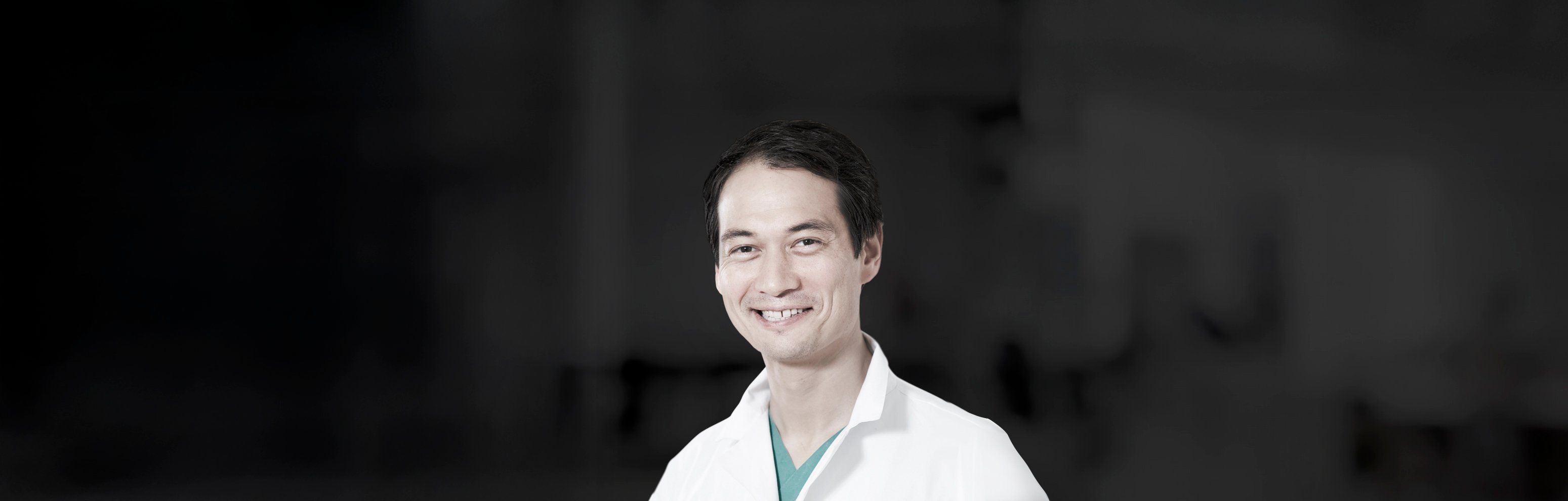Portrait of Prof Dr med Kai Januschowski from Augenklink St Petersburg, Germany, smiling in clinical attire against a dark background