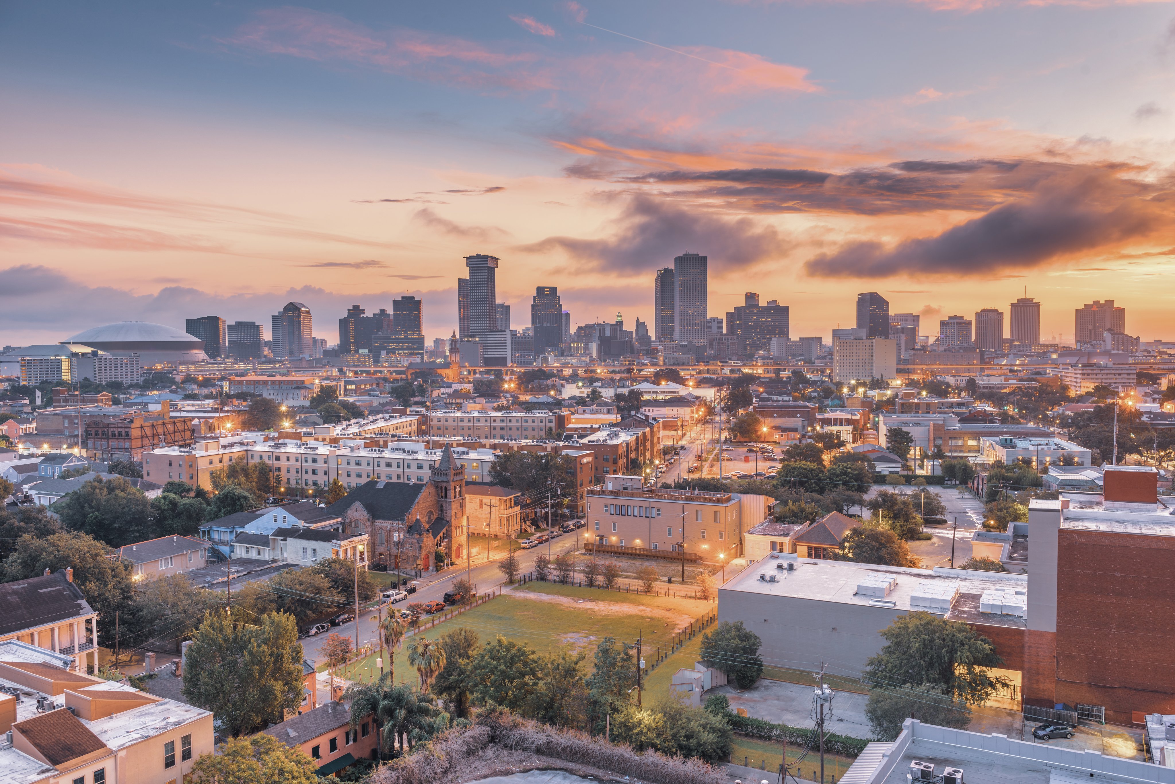 New Orleans skyline at sunset with city buildings and warm evening light, representing the congress location