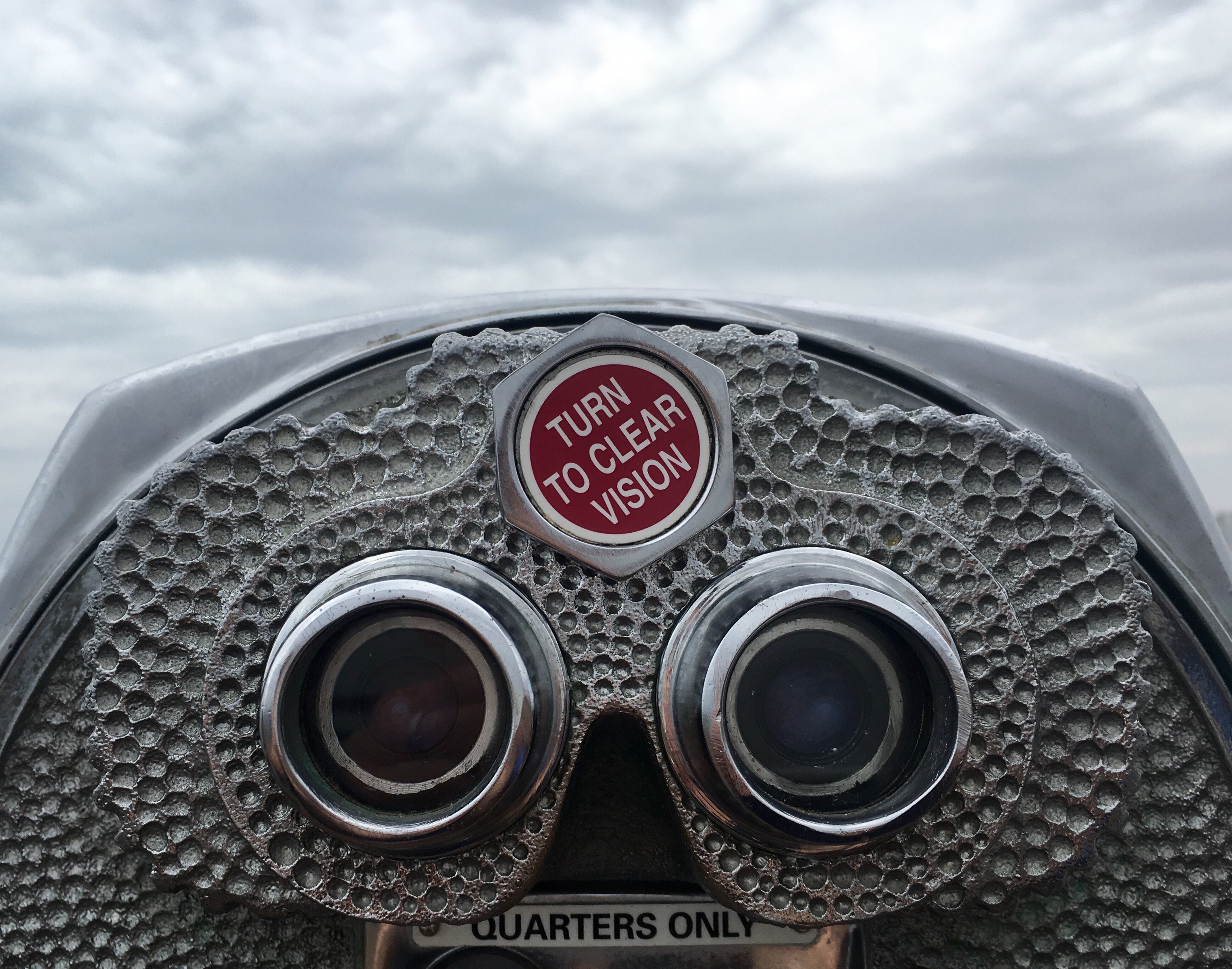 Coin-operated binocular viewer with the message “Turn to clear vision”, symbolising perspective, focus and clarity in eye surgery
